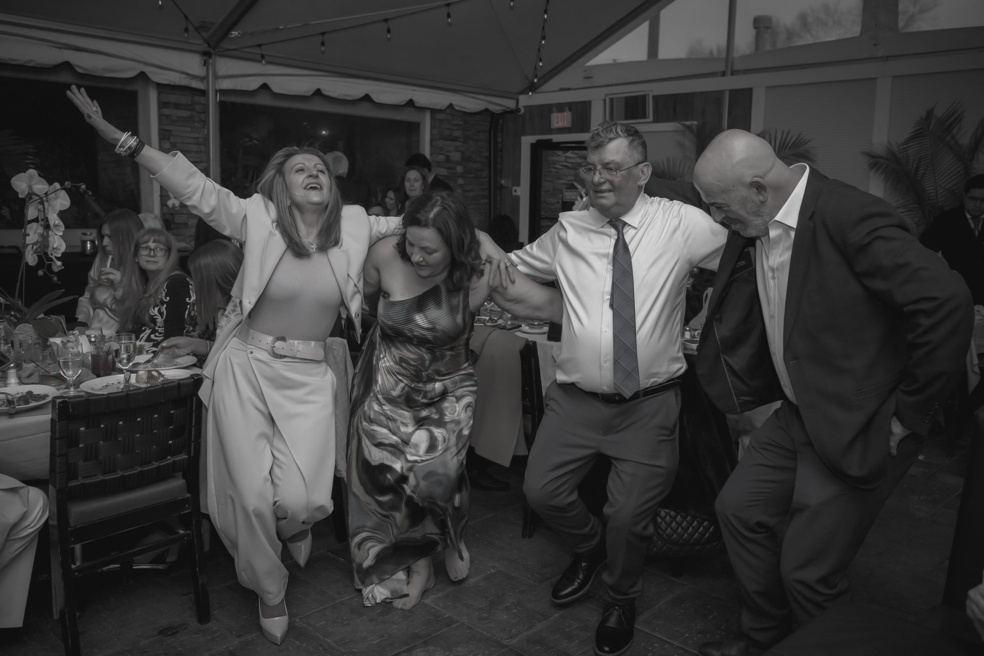 Group of people dancing and celebrating at a party in a decorated indoor venue, smiling and enjoying themselves