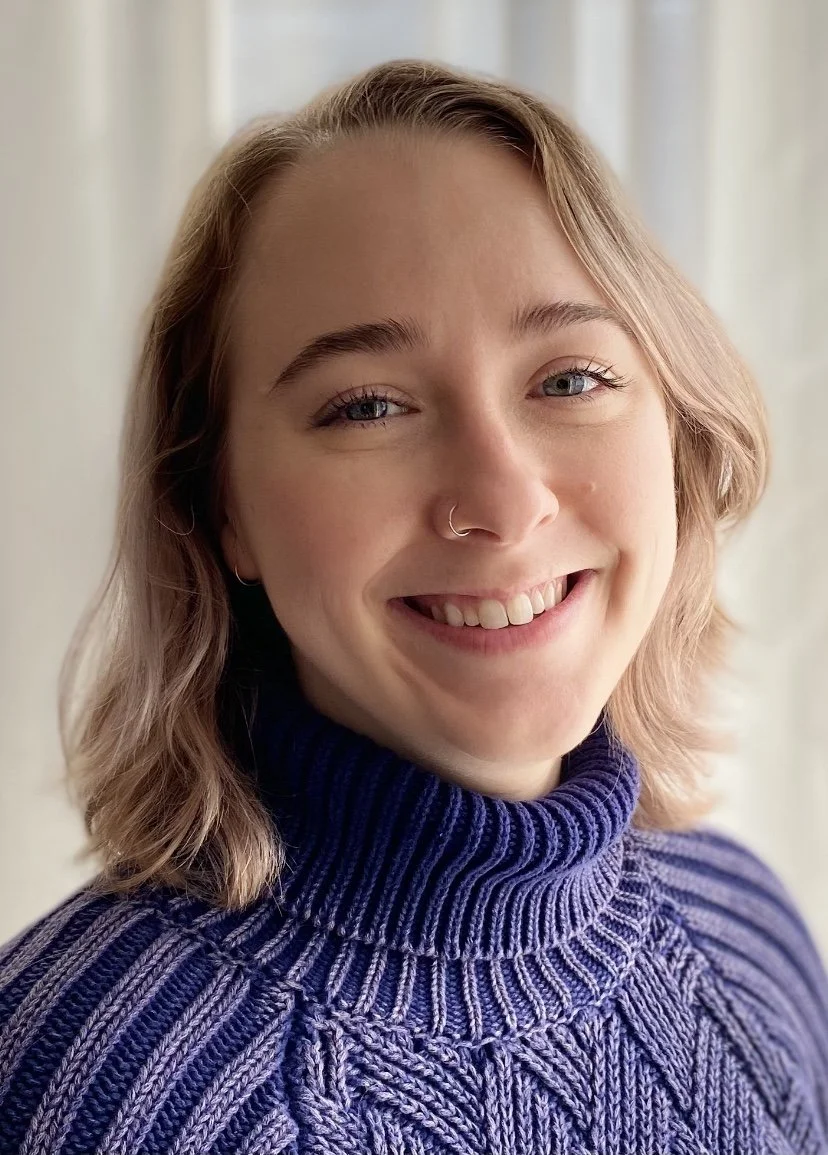 white person with shoulder length blond hair smiling at camera