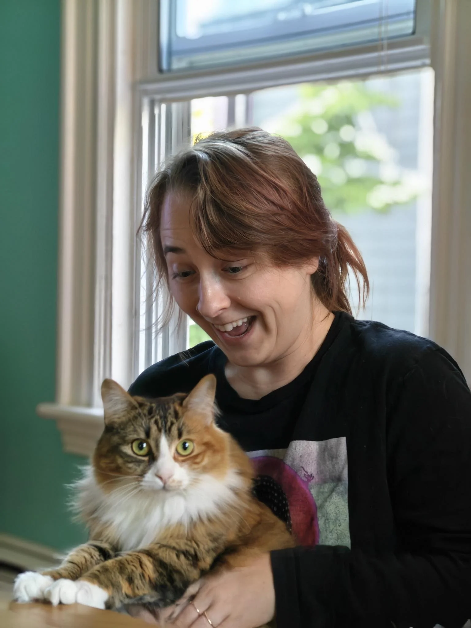person smiling with excitement at fluffy white orange white cat