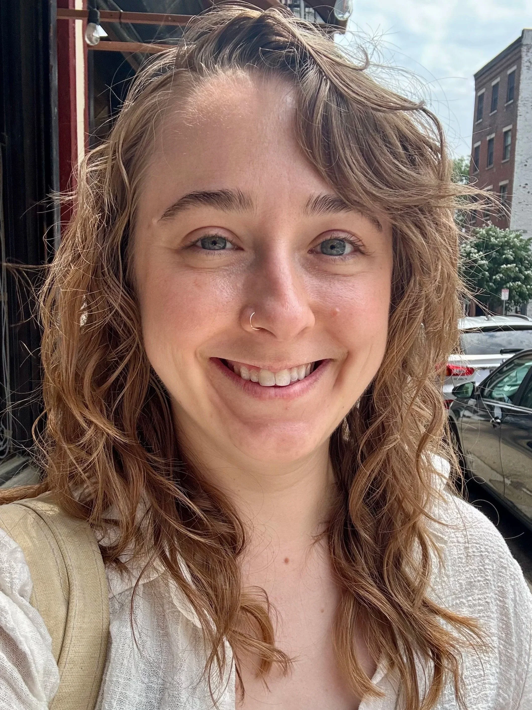 white person with wavy light brown hair smiling at camera on sunny day in Boston