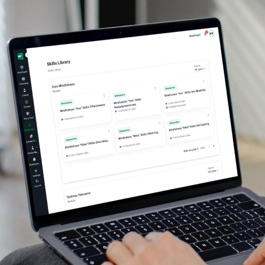 Laptop screen displaying an online skills library with various mindfulness and skills courses, with someone using the trackpad.