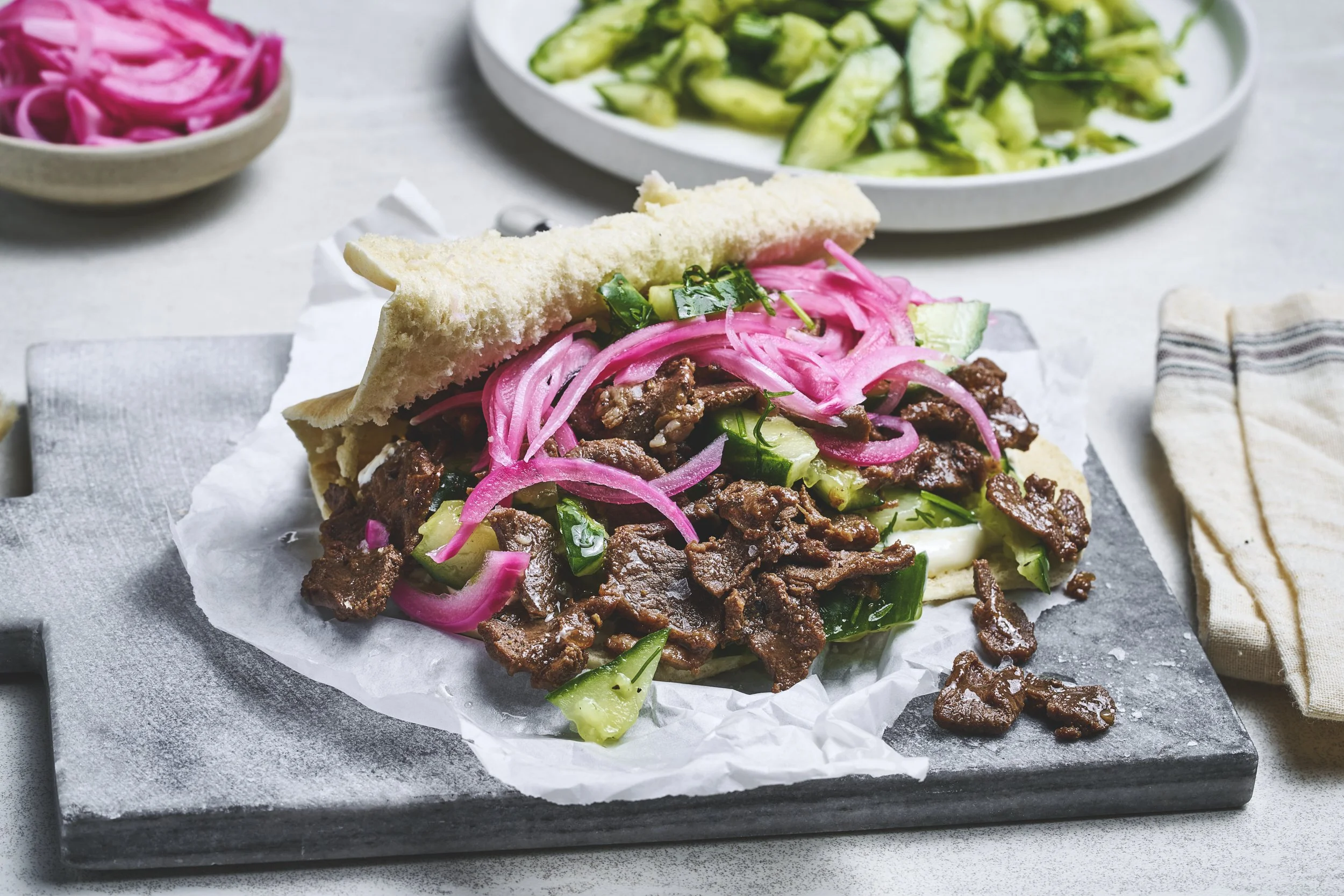 Finnbiff i pita med rømme agurksalat og syltet rødløk