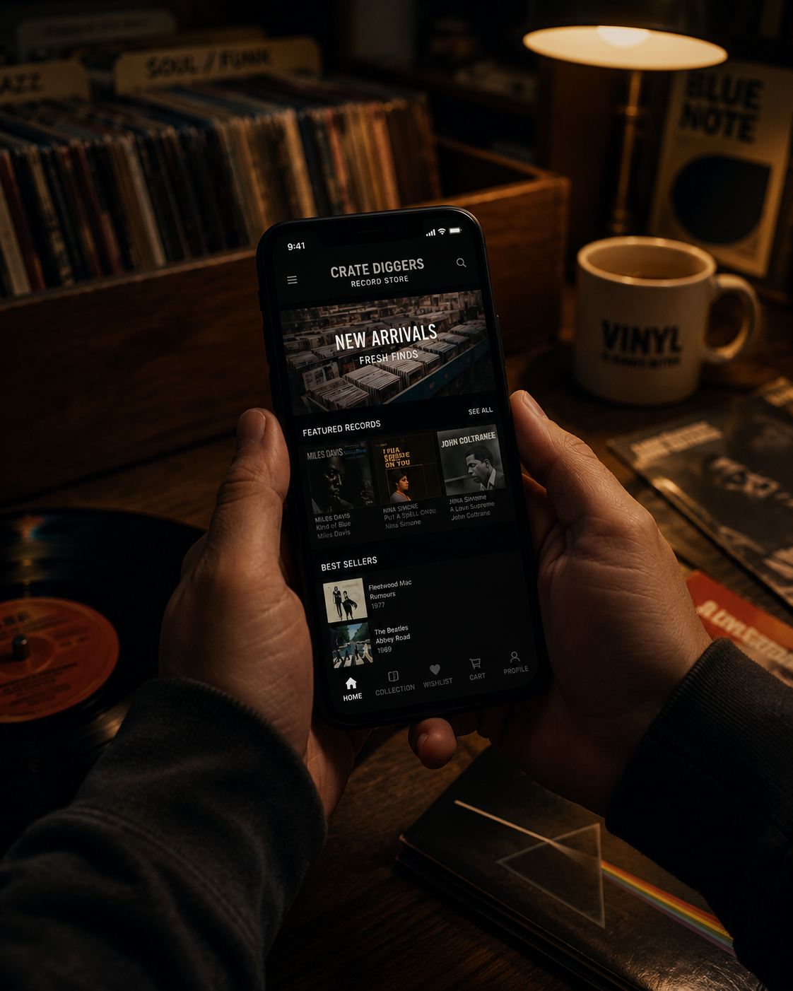 A person holding a smartphone displaying a vinyl record store app called 'Crate Diggers' with sections for new arrivals, featured records, and best sellers. The background shows a wooden table, a cup labeled 'Vinyl', a record player with a red label, and vinyl records. A warm table lamp light illuminates the scene.