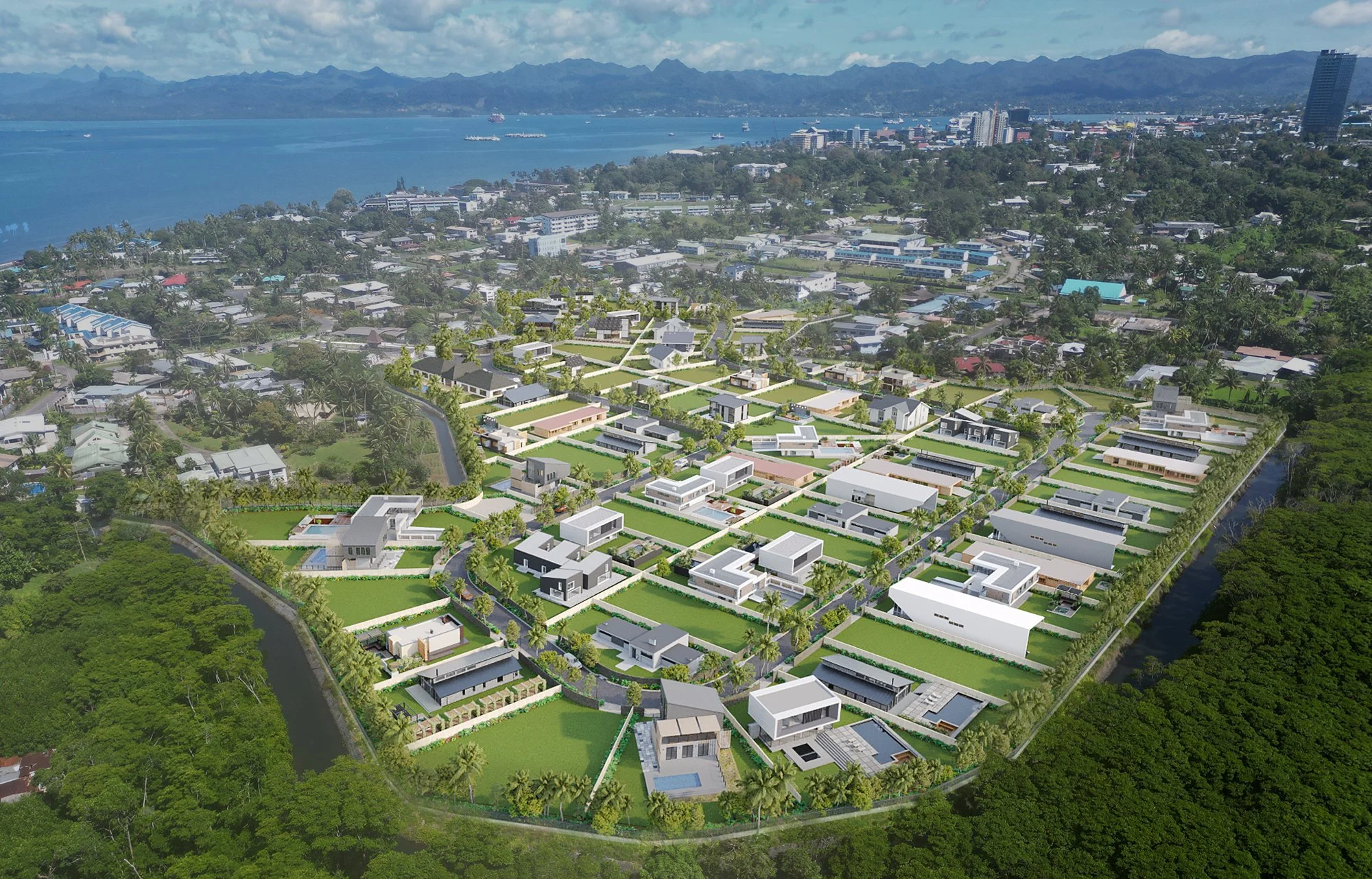 Aerial view of a residential development with modern houses, green lawns, and palm trees near a body of water with mountains in the background.