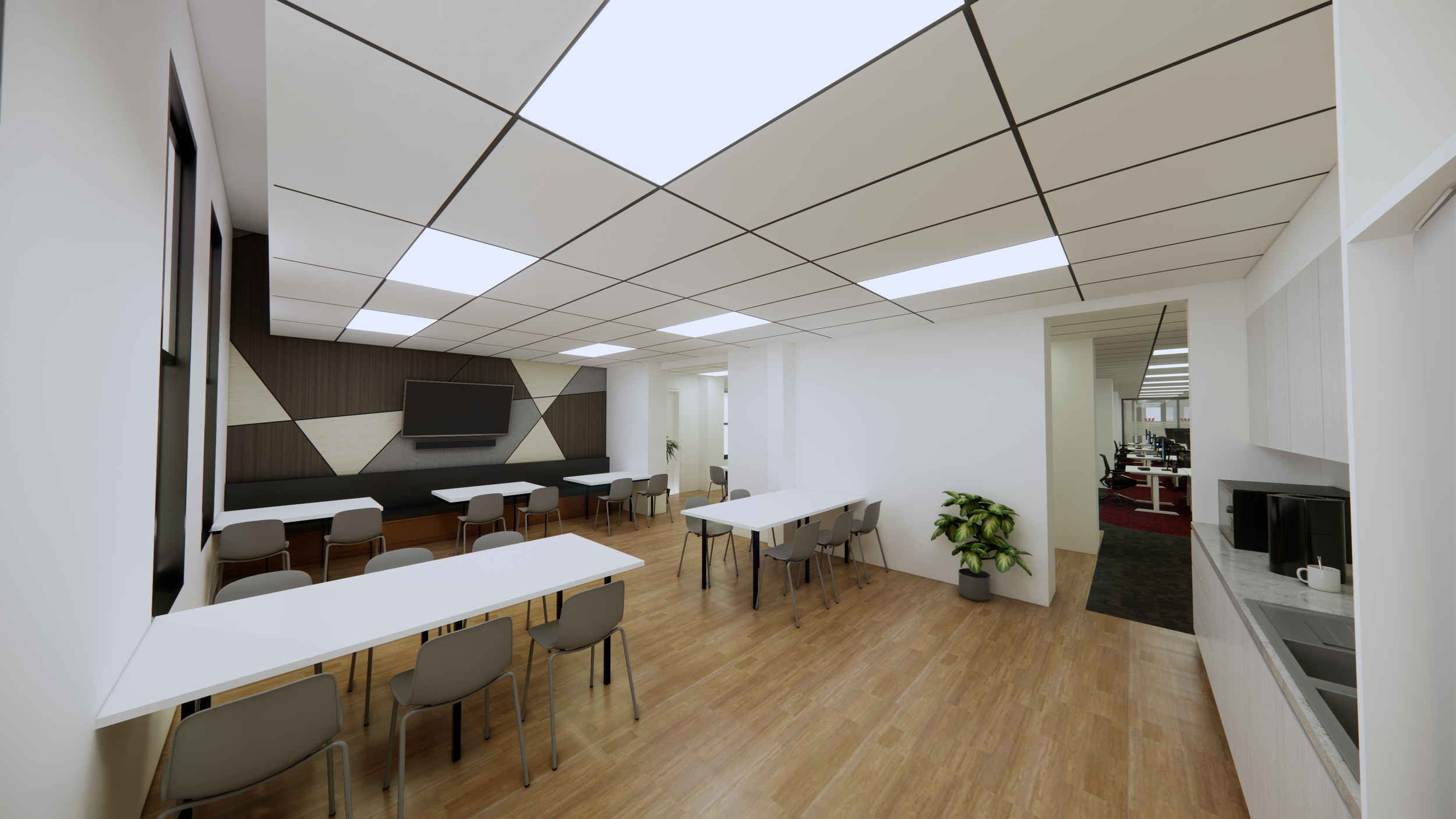 Modern conference room with white walls, wooden floors, ceiling tiles, a large TV on a wood-paneled accent wall, and several white tables and gray chairs arranged for a meeting. There is a kitchenette with a sink, microwave, and coffee mugs, and a do