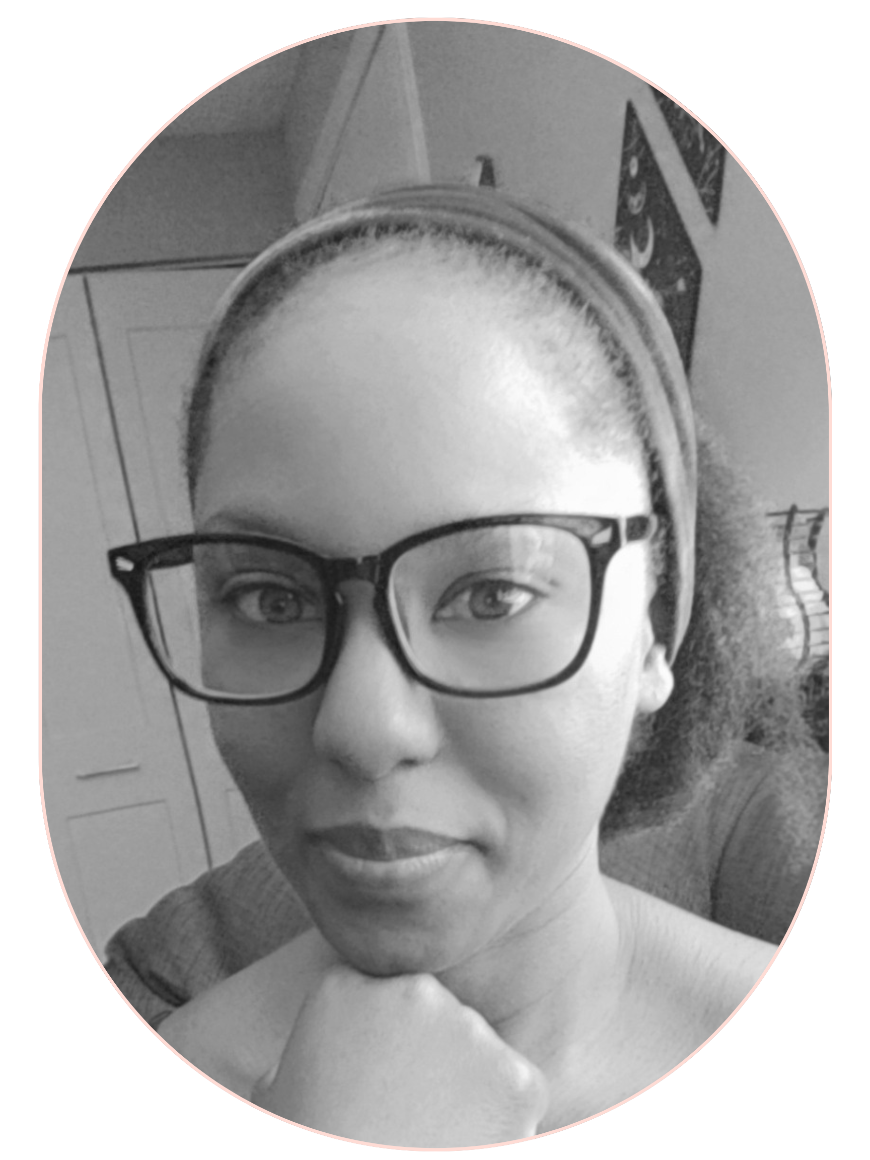 Black and white headshot of freelance wellness writer Colette Mompoint, wearing glasses and a headband, resting her chin on her hand.
