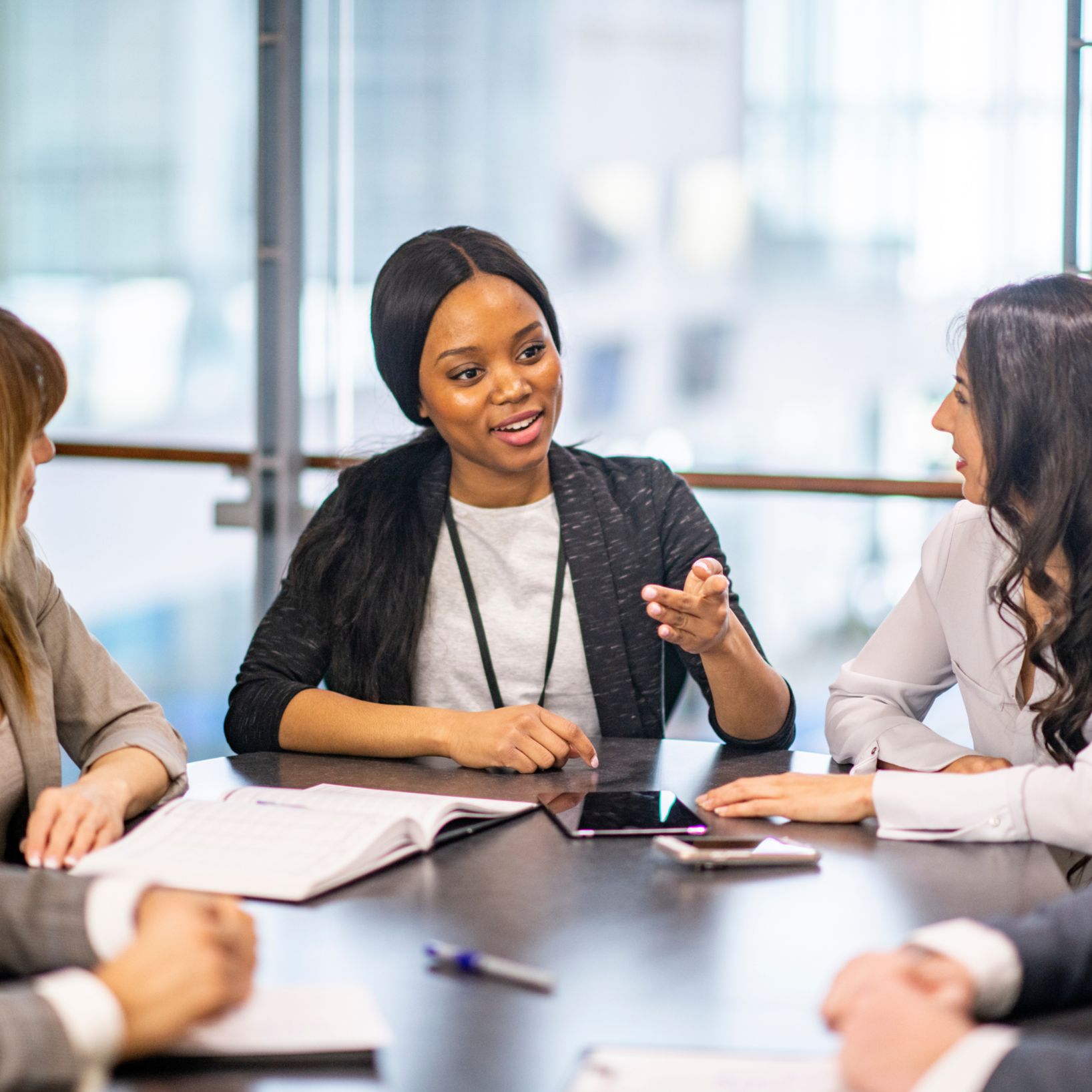 A diverse group of women having a discussion in a modern office conference room.