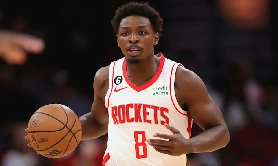 A basketball player in a Houston Rockets jersey holding a basketball