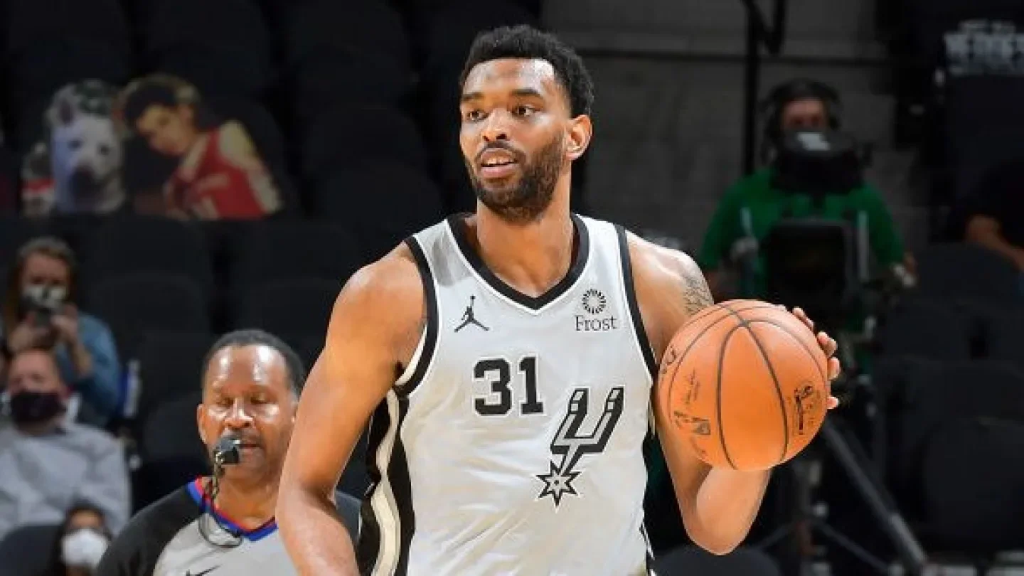 A male basketball player wearing a San Antonio Spurs jersey with the number 31 holding a basketball on the court during a game.