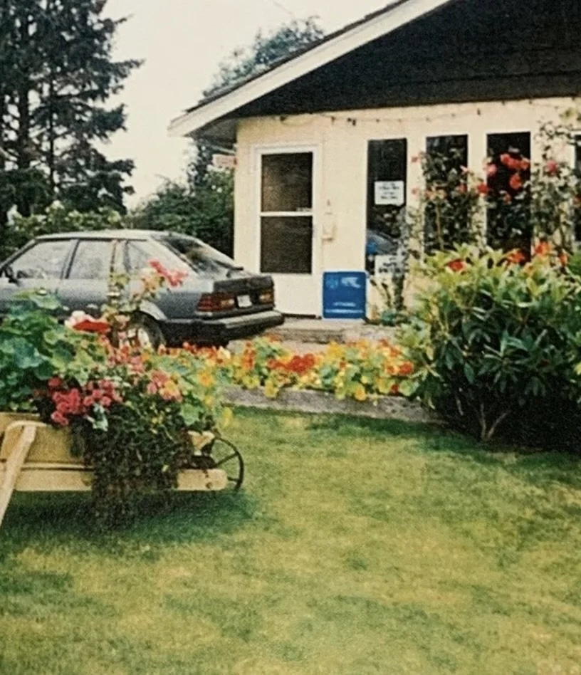 A house with a garden, a parked car in front, and colorful flowers surrounding the area.
