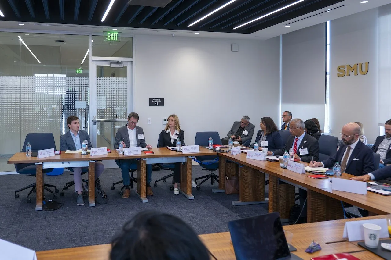 Business meeting with diverse attendees seated around a U-shaped table in a conference room at SMU.