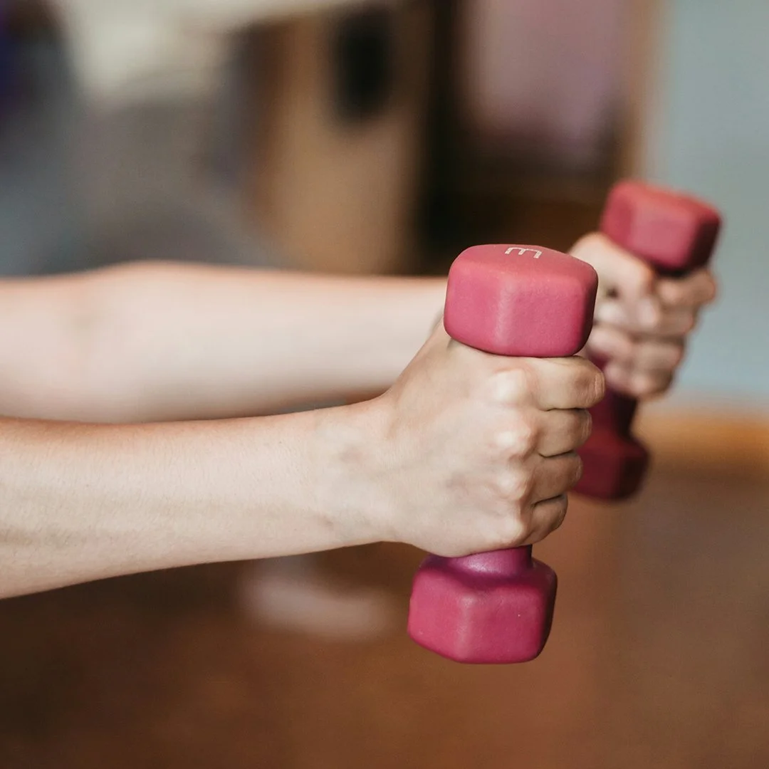 Person holding pink dumbbells.