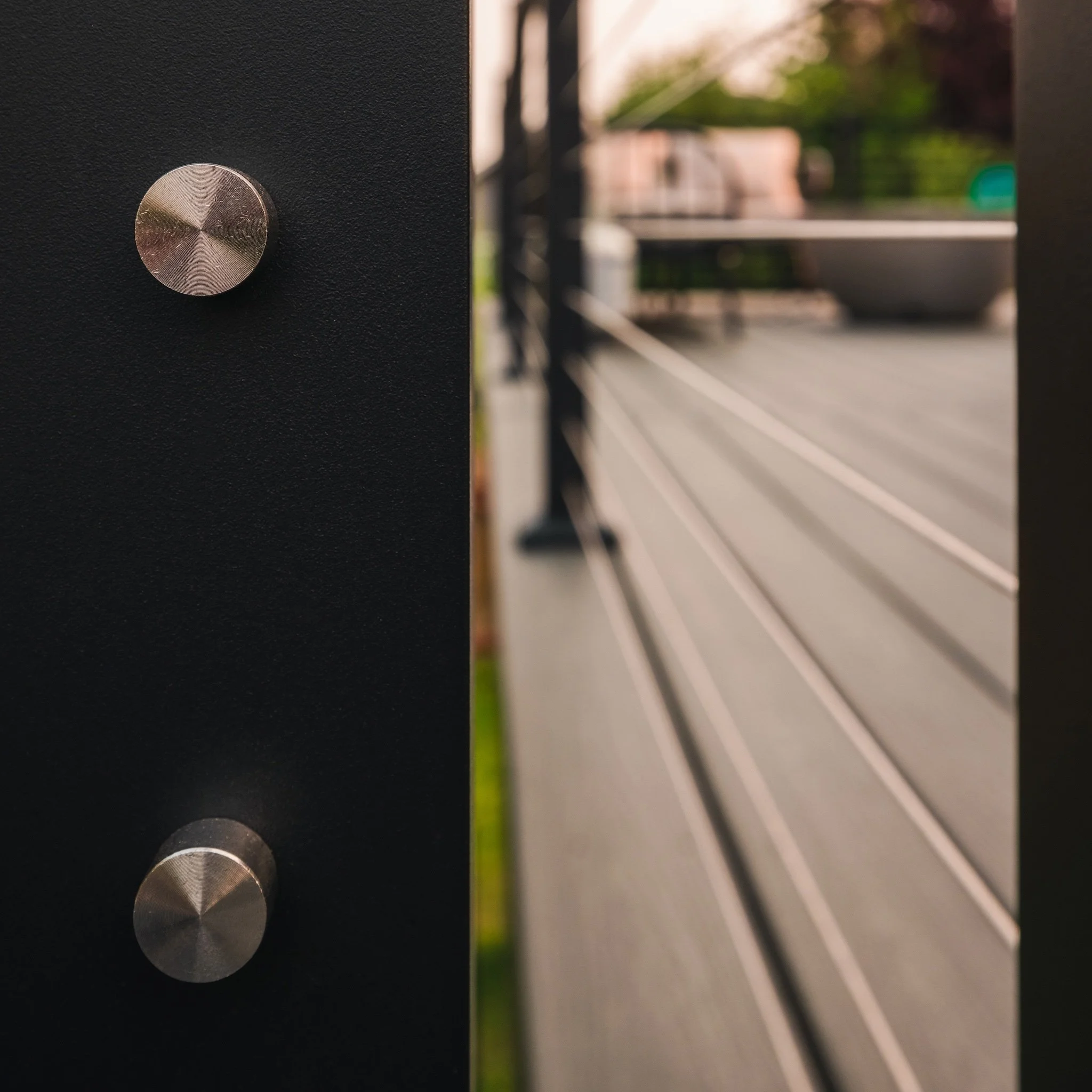 Close-up of black metal railing with two round metallic knobs.