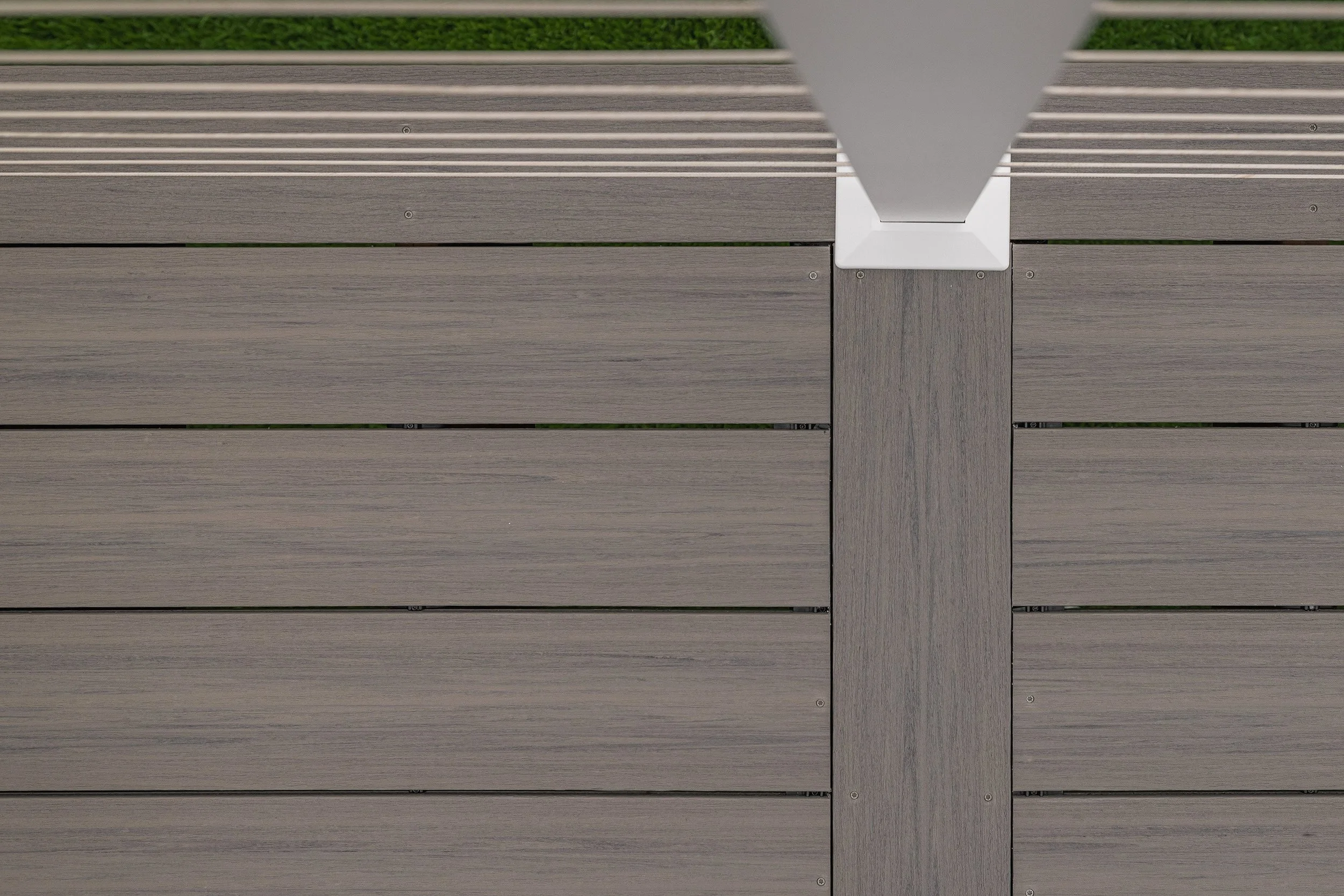 Close-up of a deck with gray composite decking, with white aluminum cable railing