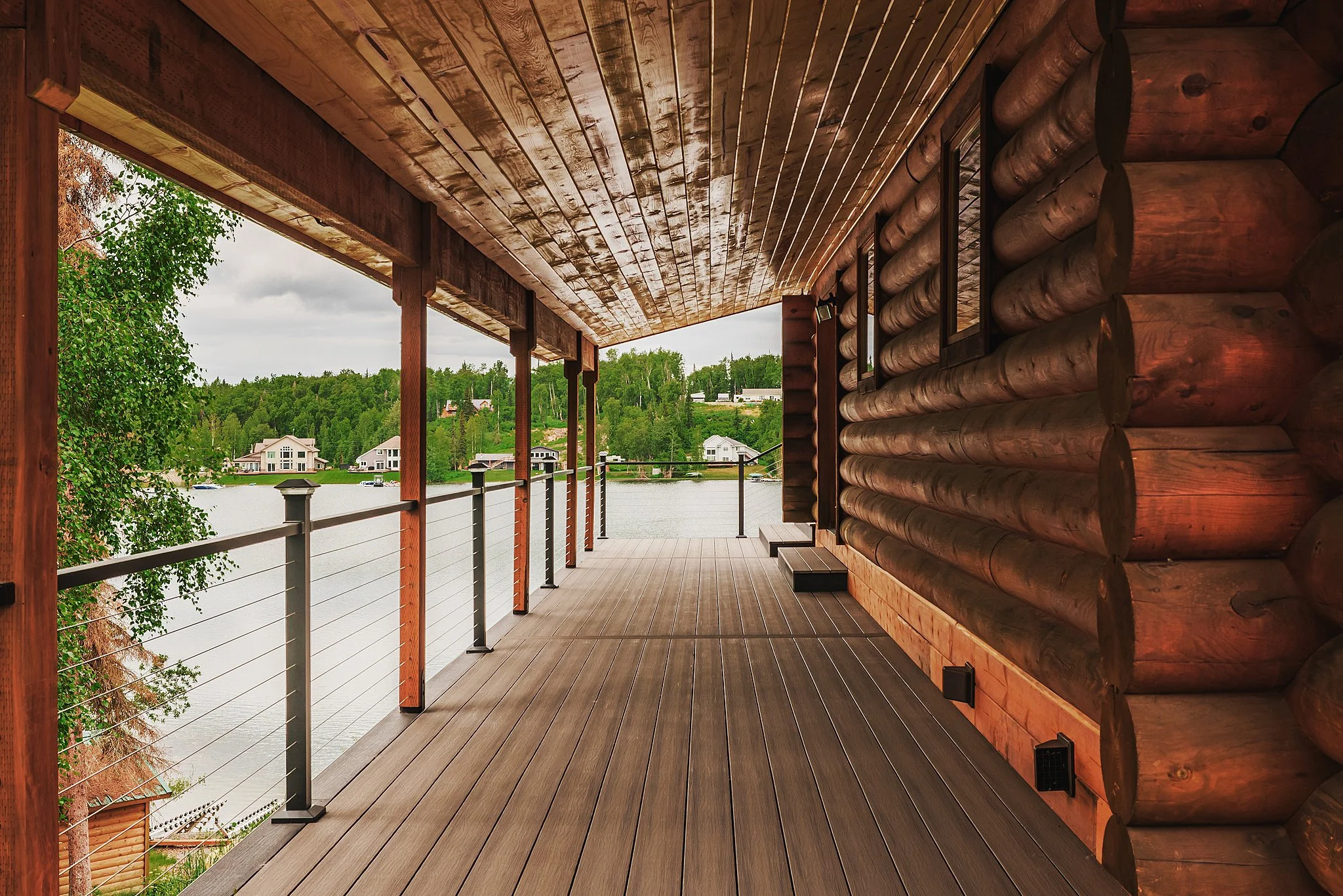 A composite decking balcony overlooking a lake with houses and trees in the background.