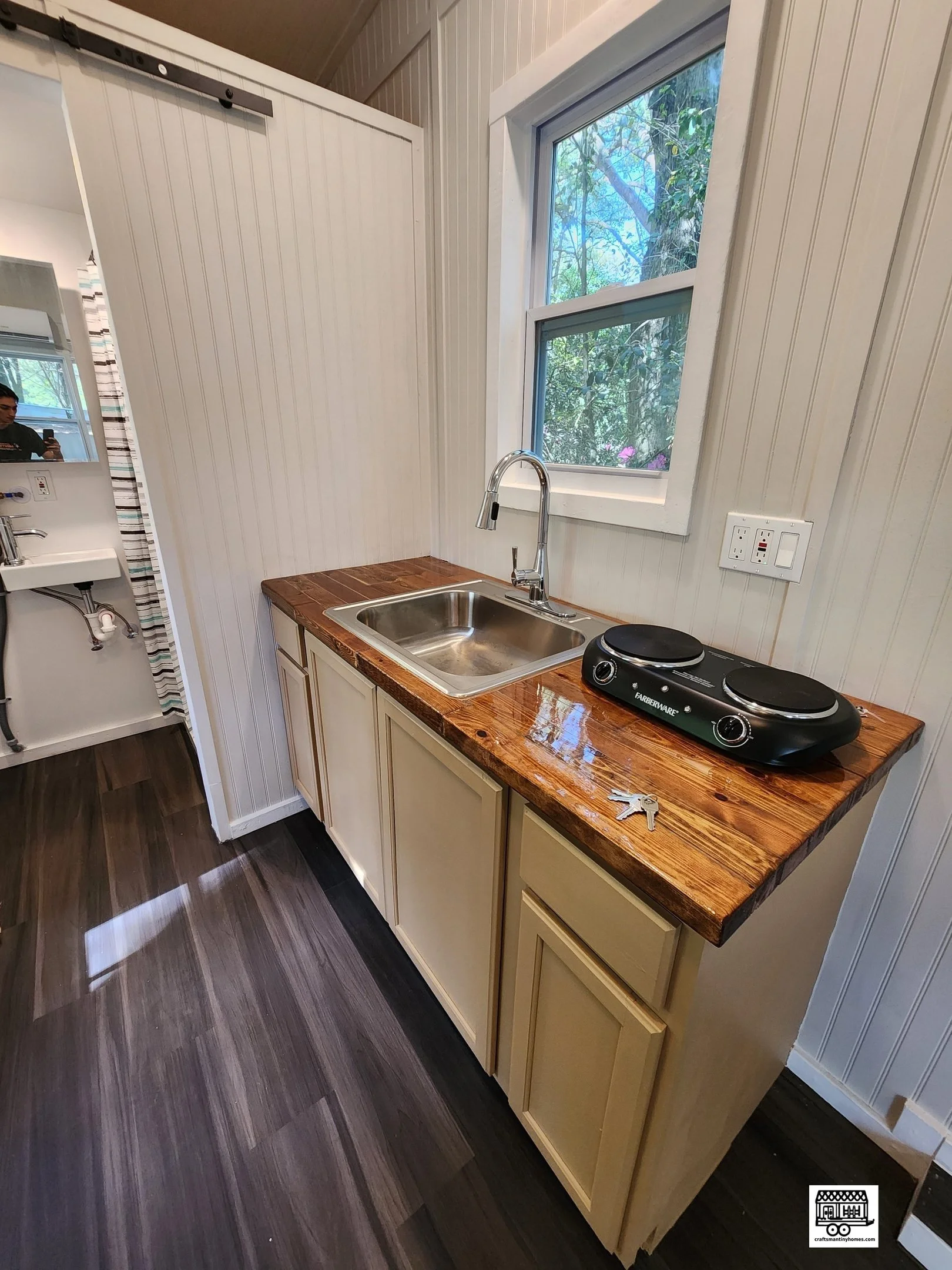 Small kitchen area with a window, sink, electric cooktop, and tile backsplash.