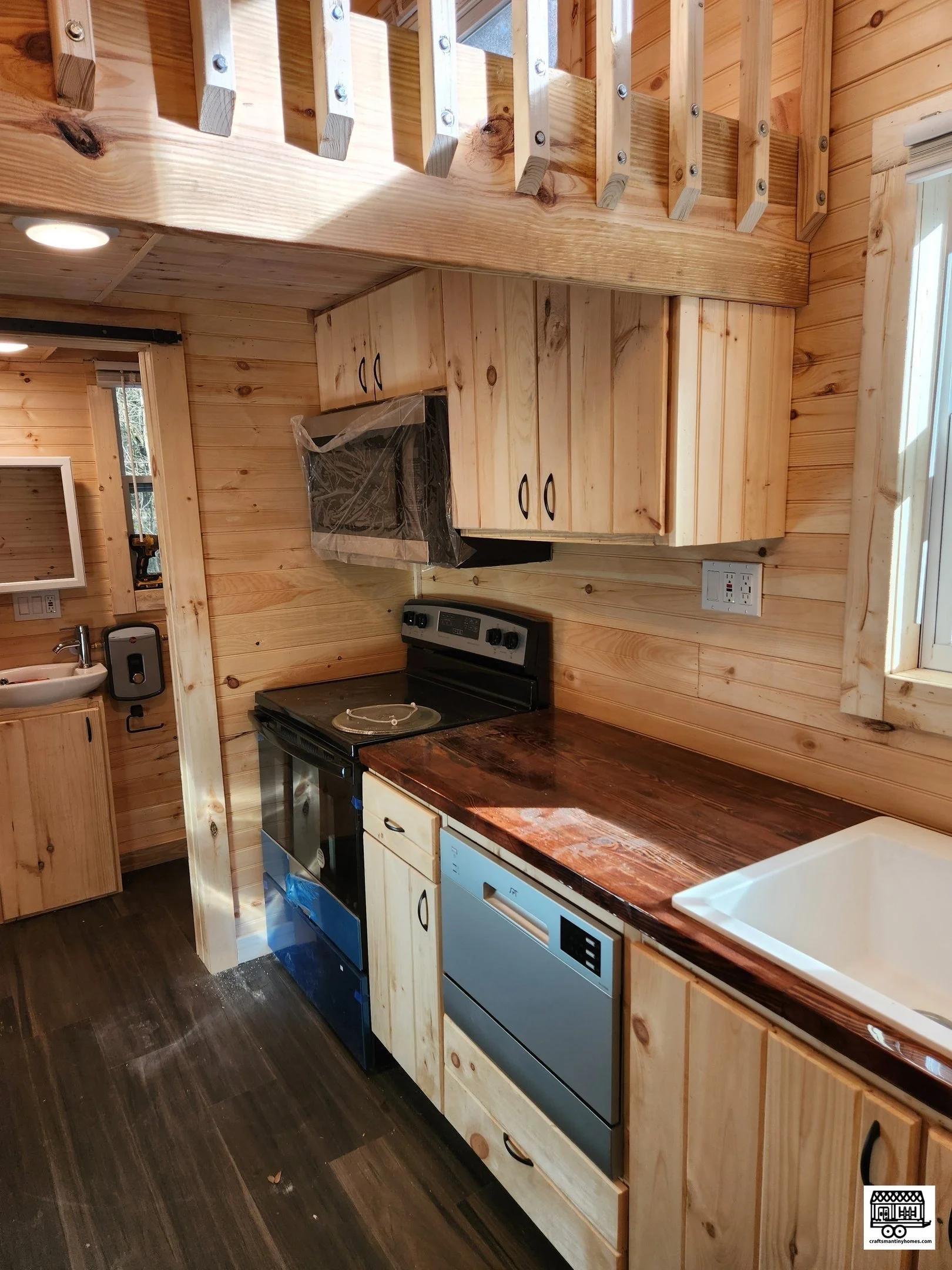 Wooden kitchen with black stove, blue dishwasher, white sink, and wooden cabinets.
