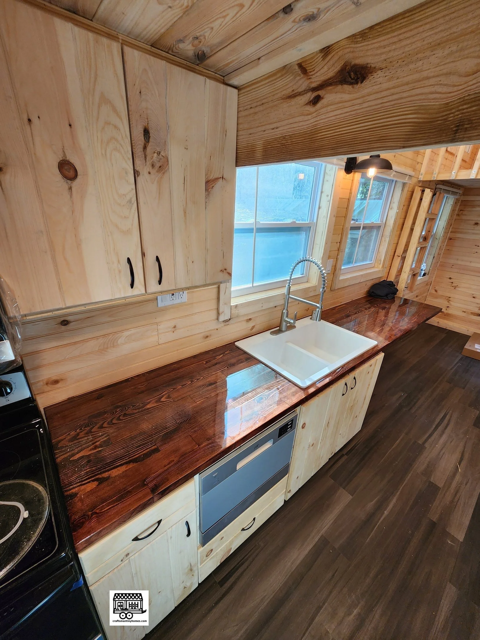 Wooden kitchen with a dark wood countertop, light wood cabinets, a white farmhouse sink, and a window above the sink.