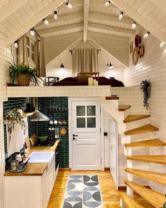 Modern A-frame tiny home interior by Crafted Tiny Homes USA, featuring a bright kitchen with green backsplash tiles, wood countertops, and a loft bedroom — an ideal design for small-space living inspiration.