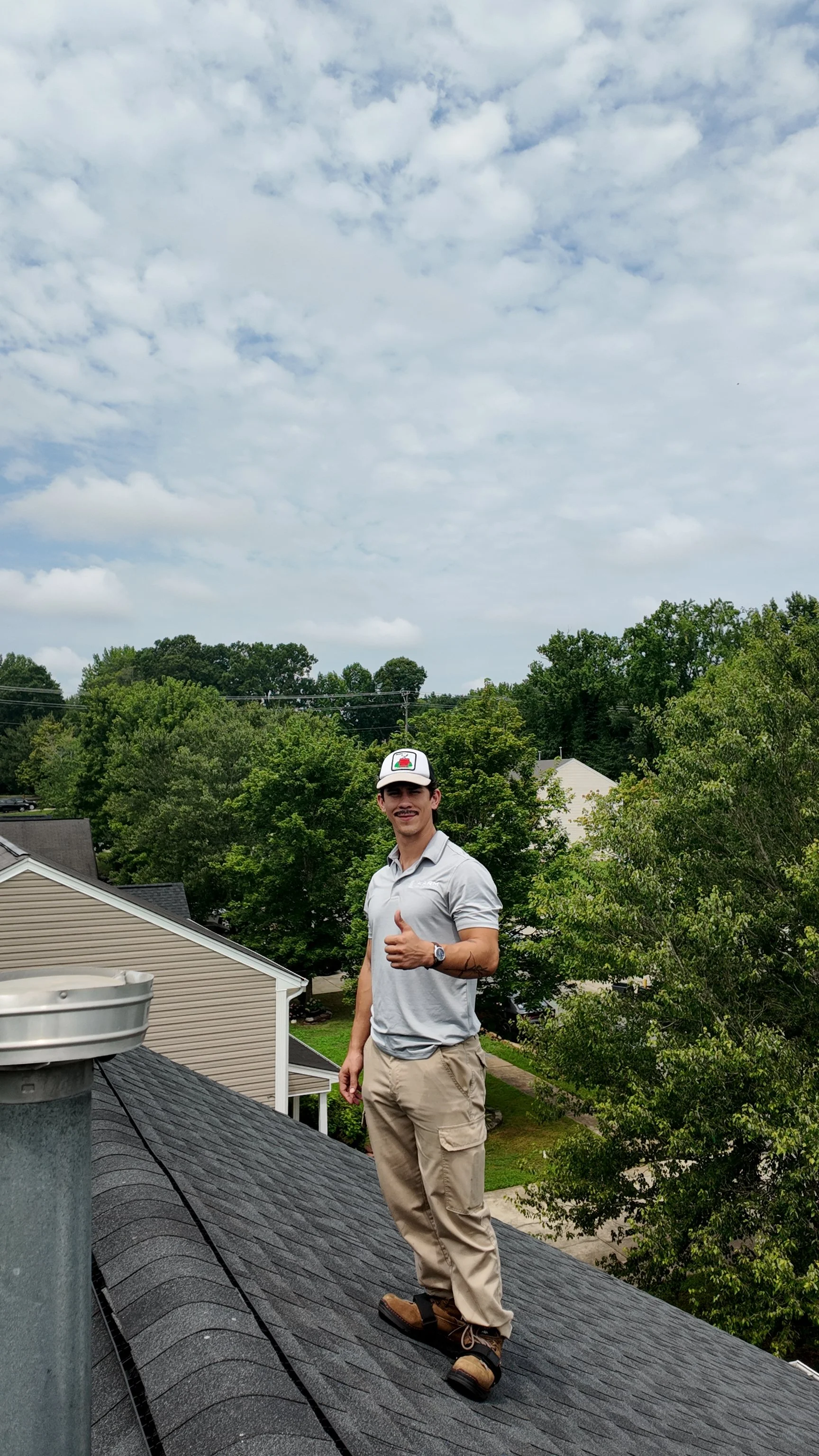 John posing on a roof with a thumbs-up gesture, while inspecting a referral home for storm damage.