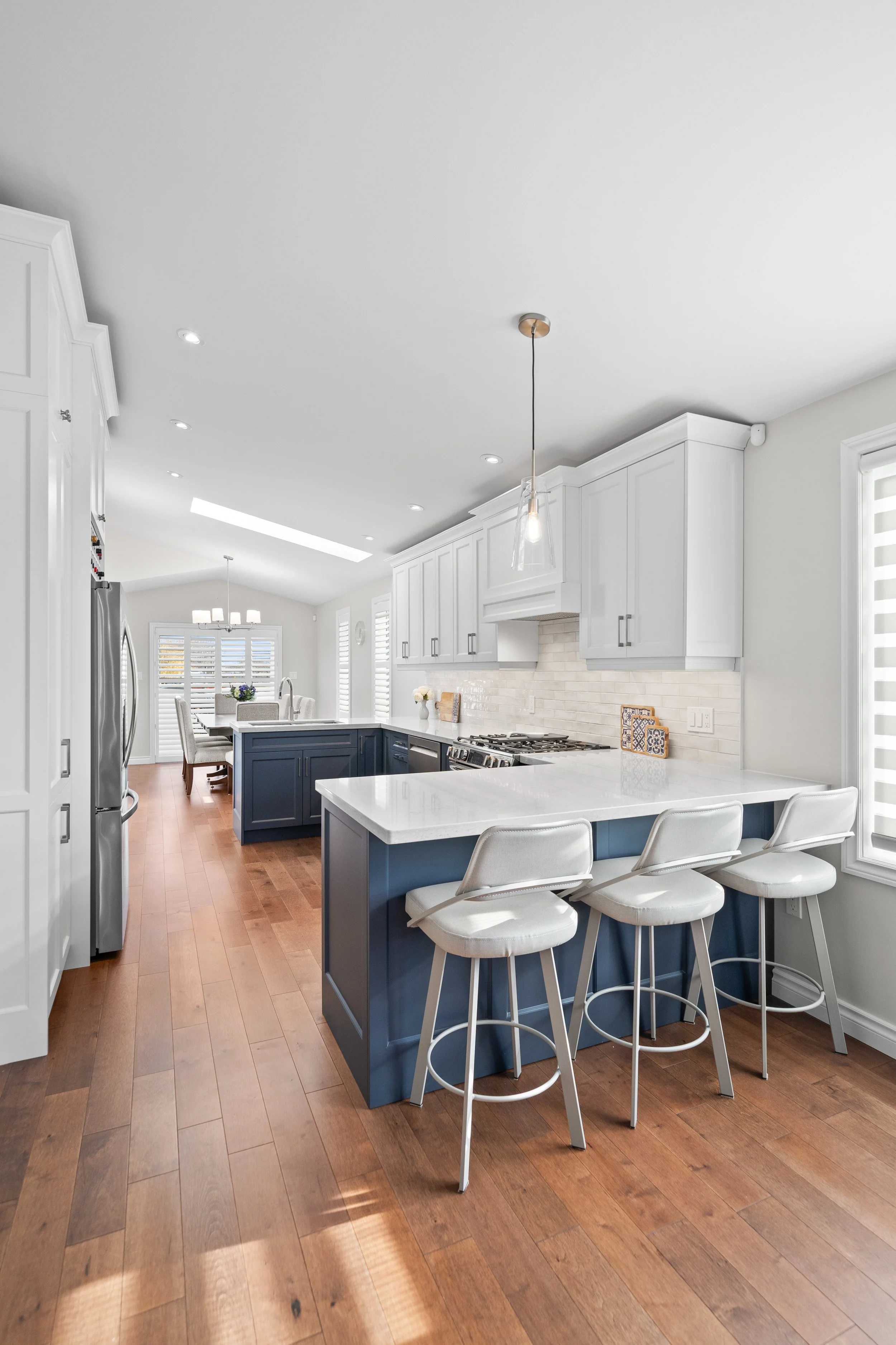 Modern kitchen with white cabinets, a blue island, and wooden flooring.