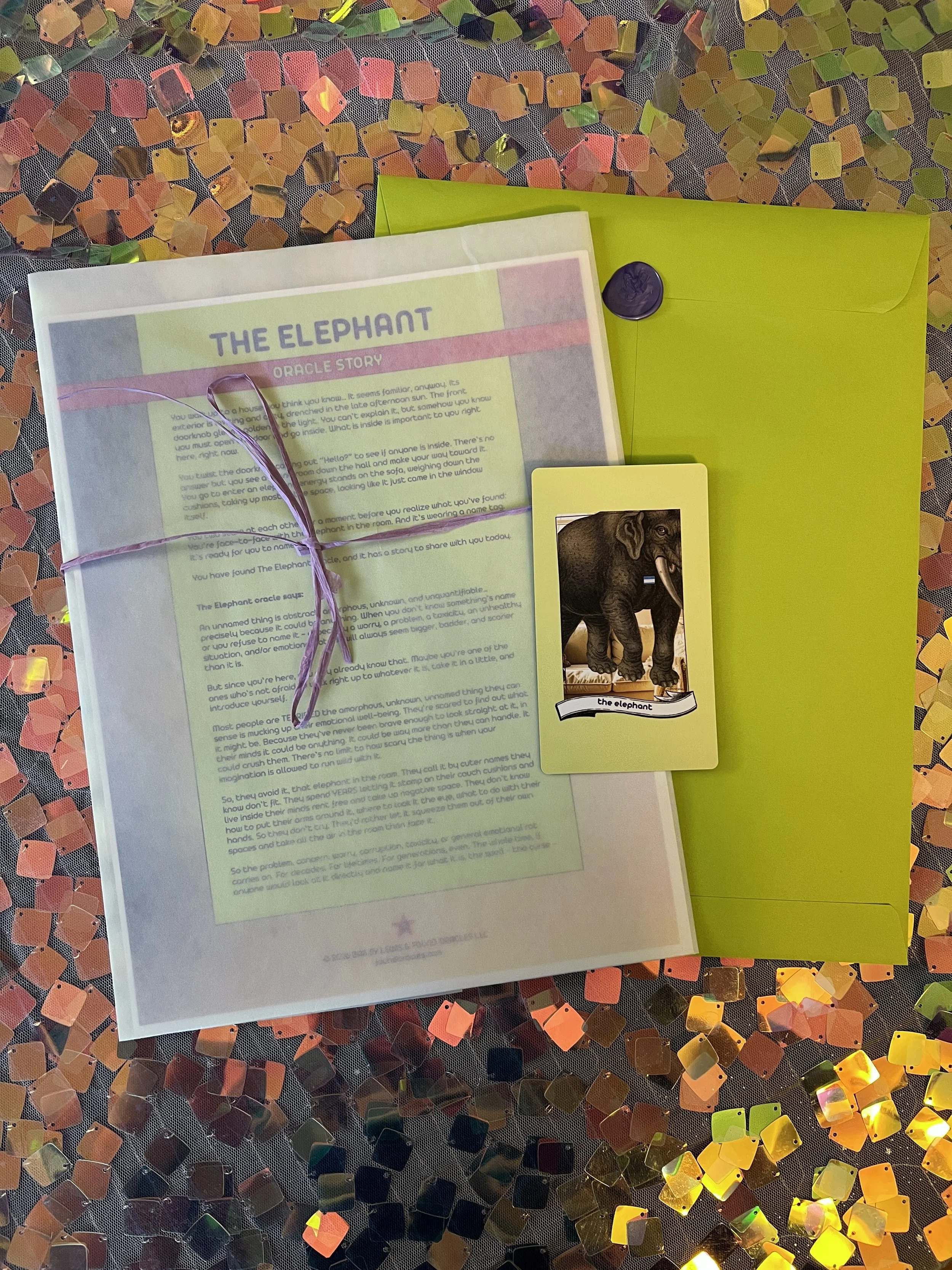 Flat lay shot of The Elephant printed story card and story sheet from Found Oracles with purple wax sealed green envelope behind.