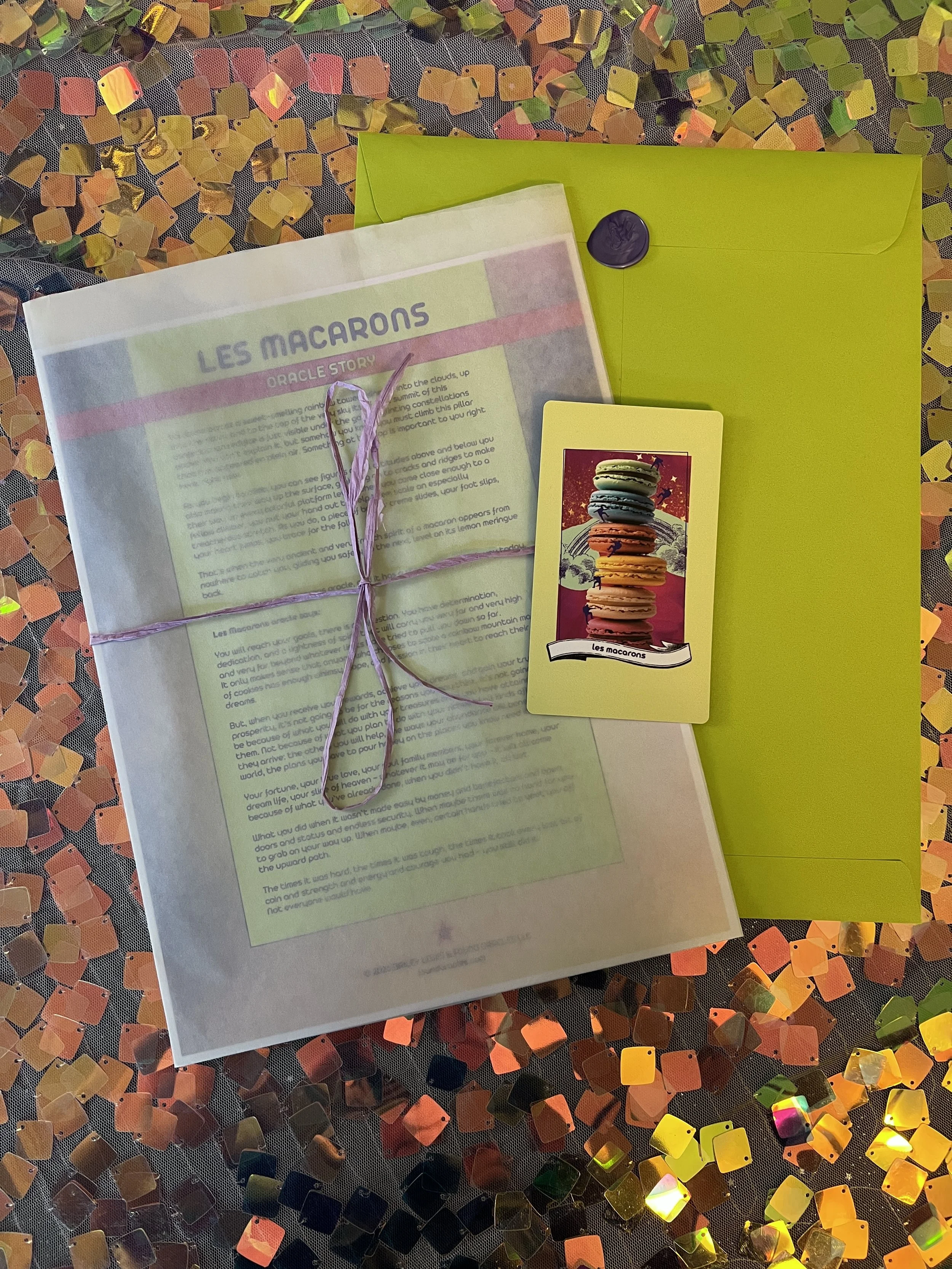 Flat lay shot of Les Macarons printed story card and story sheet from Found Oracles with purple wax sealed green envelope behind.
