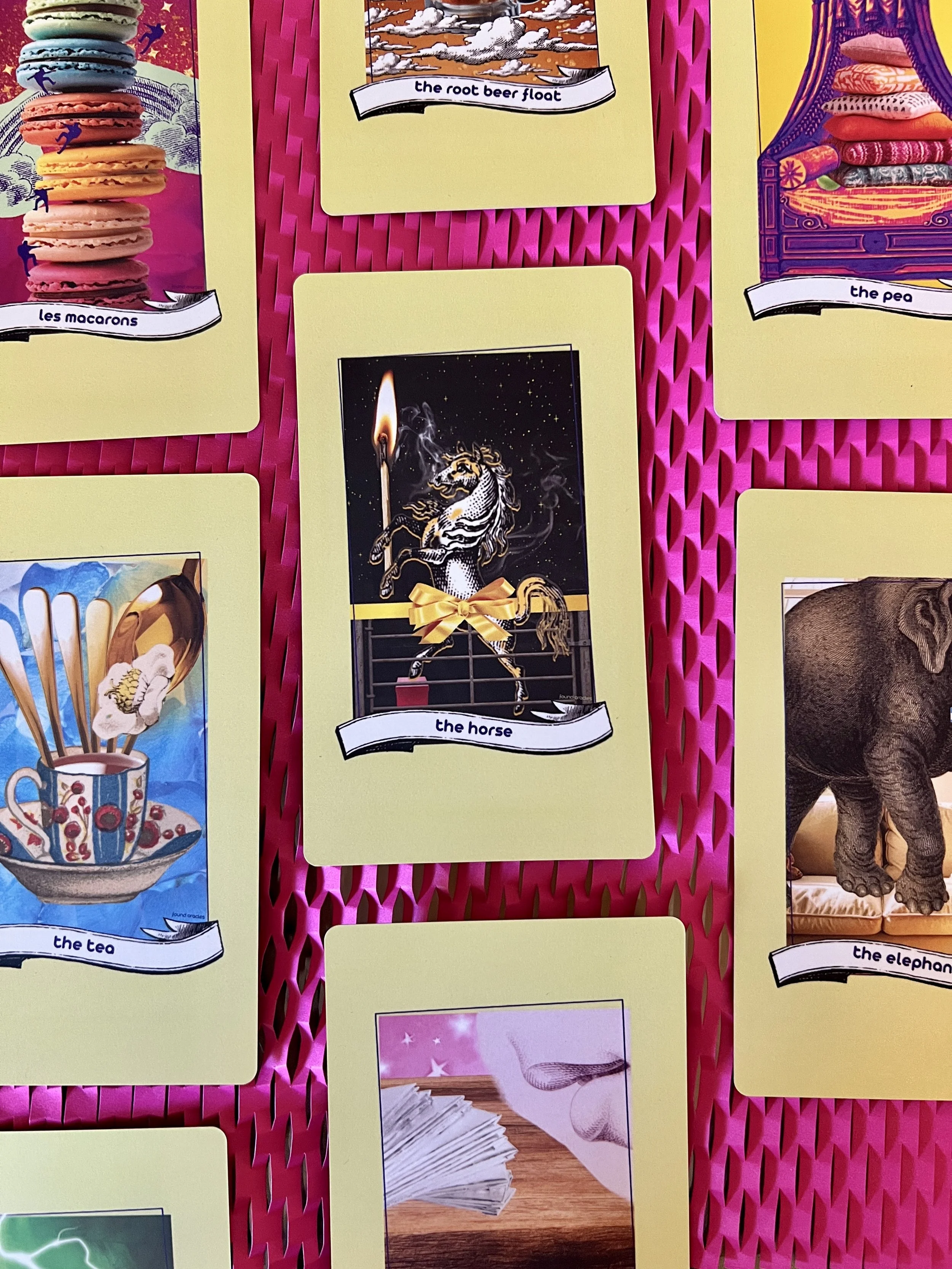 A grid of the Found Oracles cards found in the Hello World deck on a hot pink honeycomb background including The Horse, The Tea, and The Elephant.