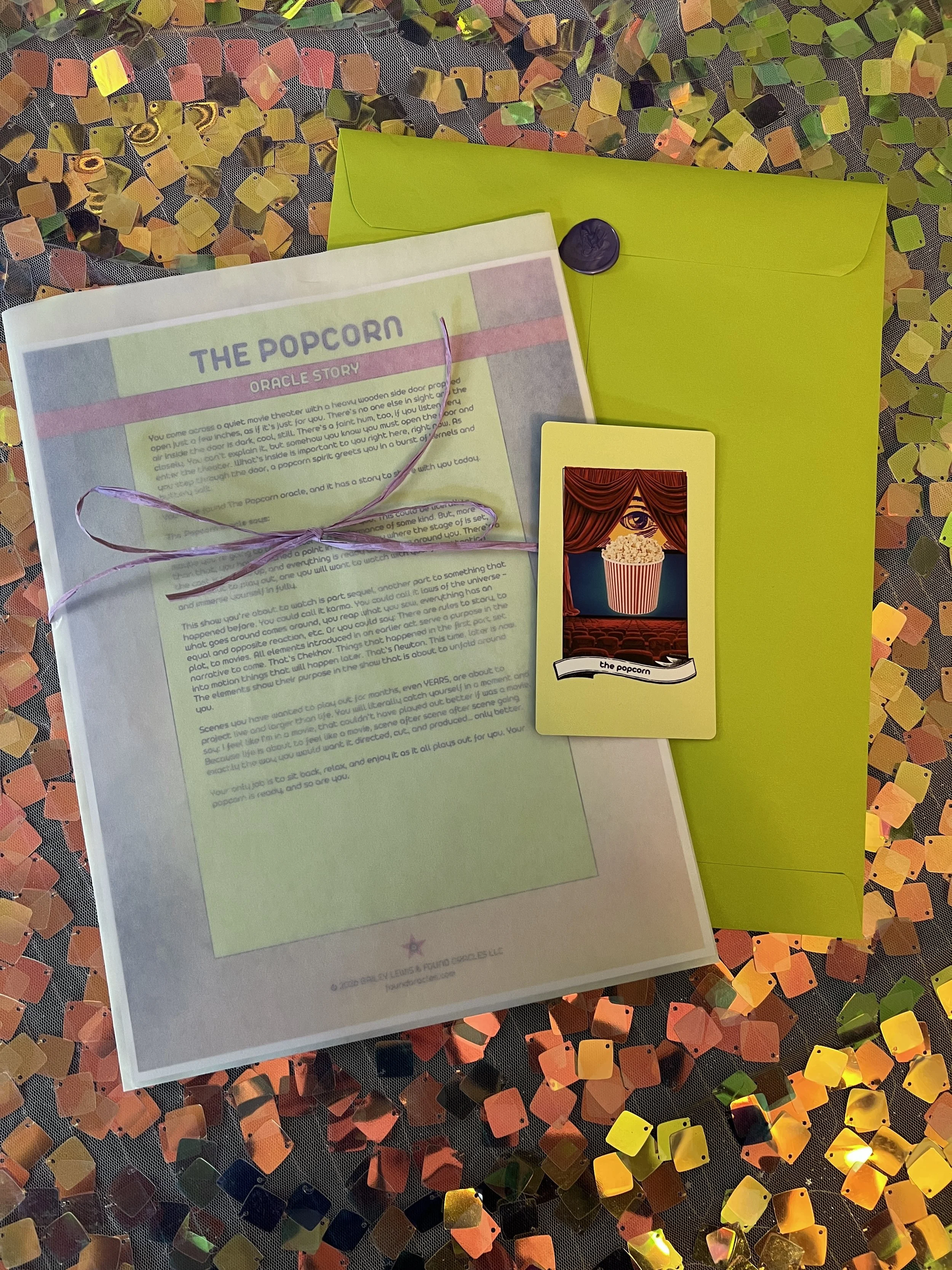 Flat lay shot of The Popcorn printed story card and story sheet from Found Oracles with purple wax sealed green envelope behind.