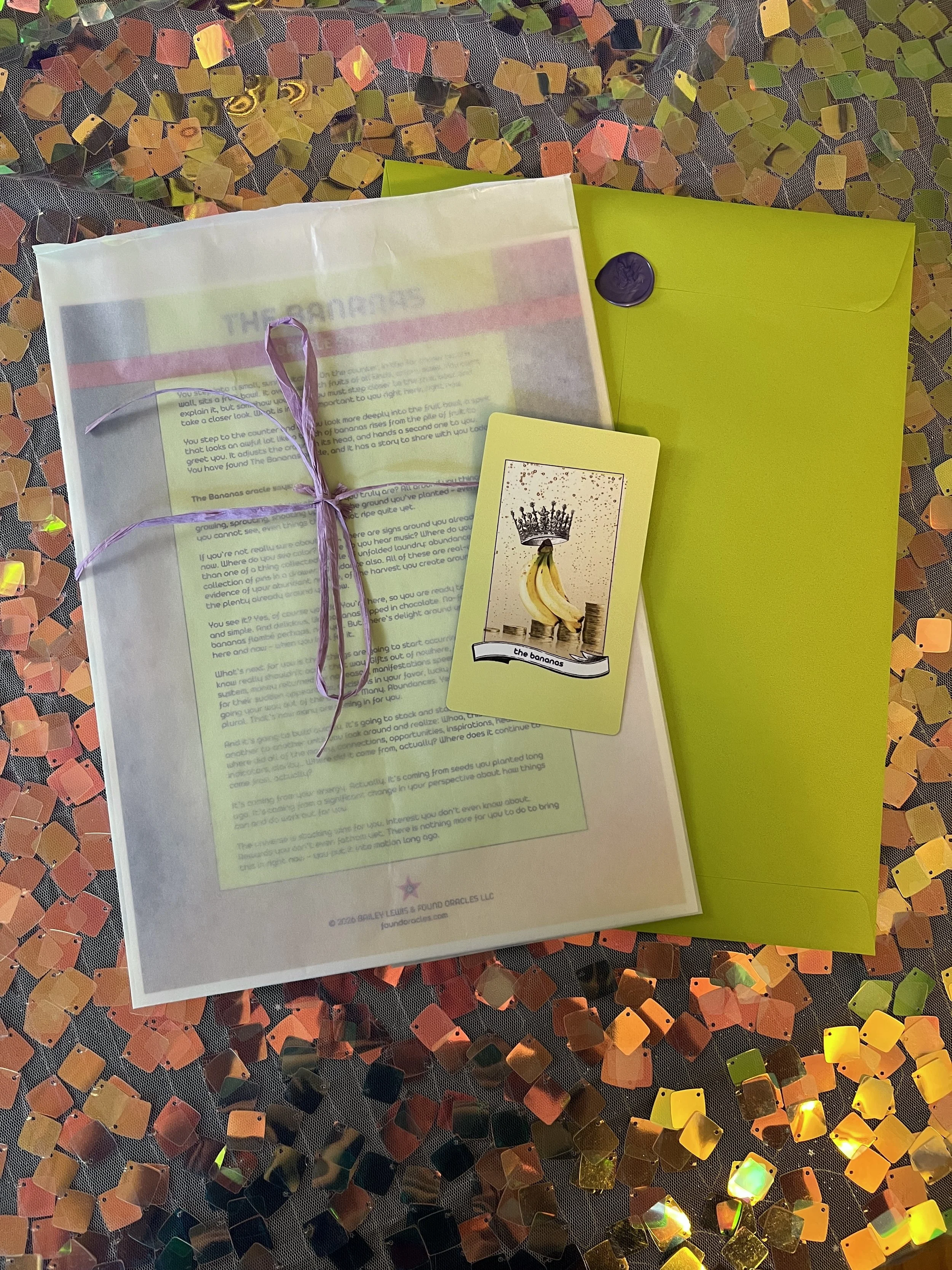 Flat lay shot of The Bananas printed story card and story sheet from Found Oracles with purple wax sealed green envelope behind.