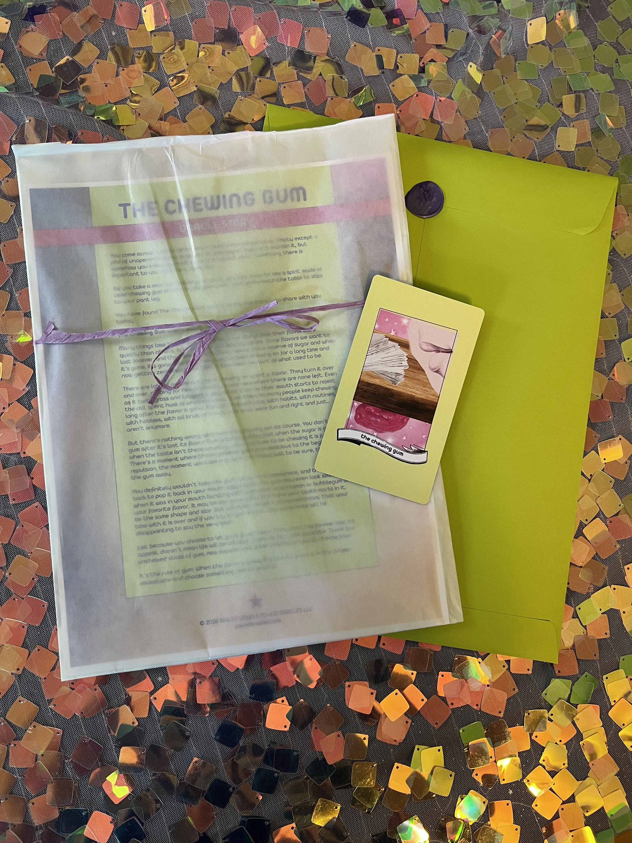 Flat lay shot of The Chewing Gum printed story card and story sheet from Found Oracles with purple wax sealed green envelope behind.