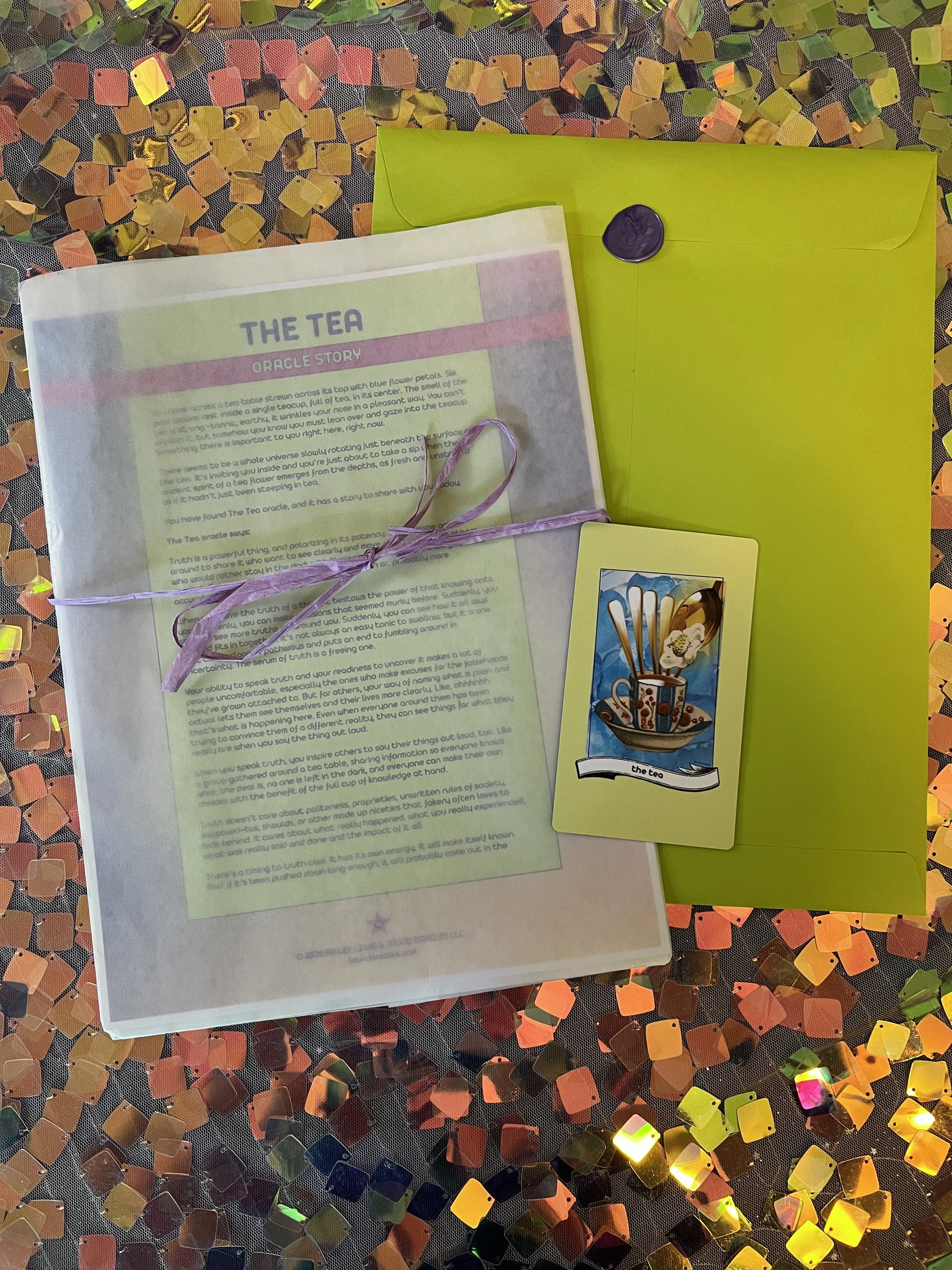 Flat lay shot of The Tea printed story card and story sheet from Found Oracles with purple wax sealed green envelope behind.