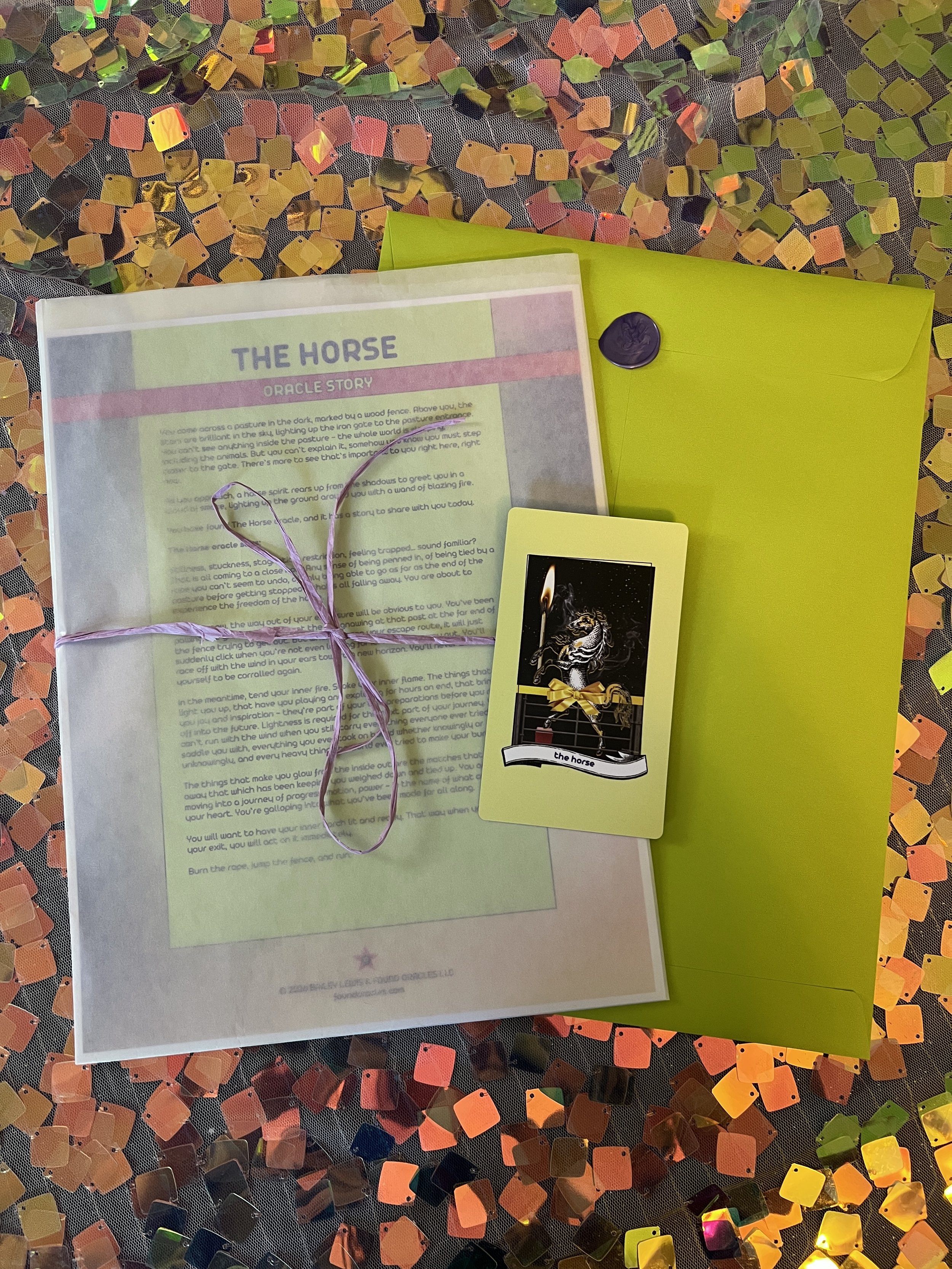 Flat lay shot of The Horse printed story card and story sheet from Found Oracles with purple wax sealed green envelope behind.