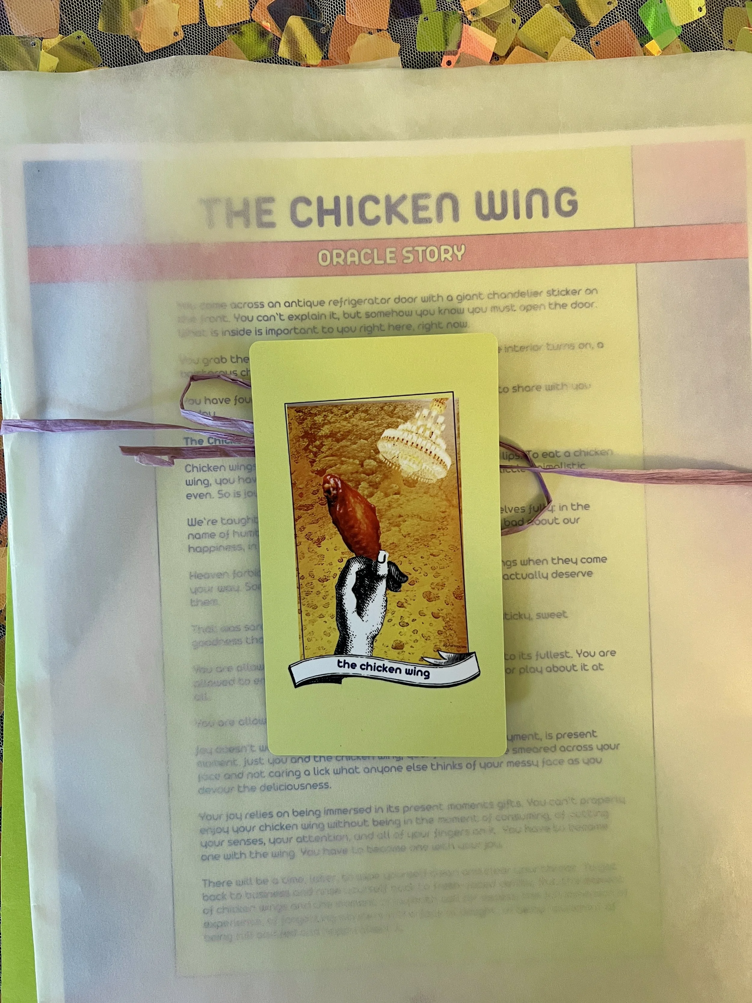 The Chicken Wing individual printed card and story sheet from Found Oracles shown bundled up with the card on top.