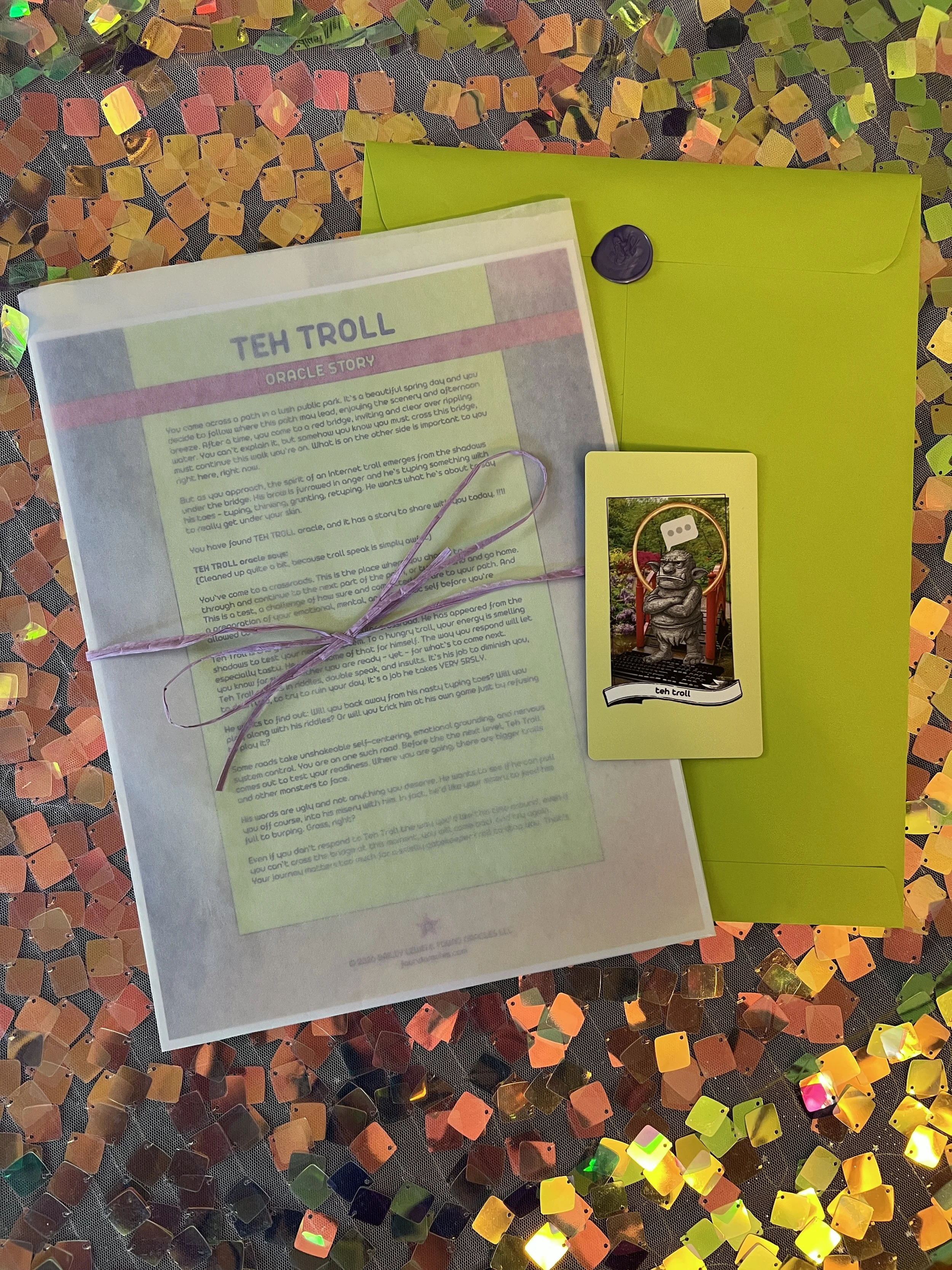 Flat lay shot of Teh Troll printed story card and story sheet from Found Oracles with purple wax sealed green envelope behind.