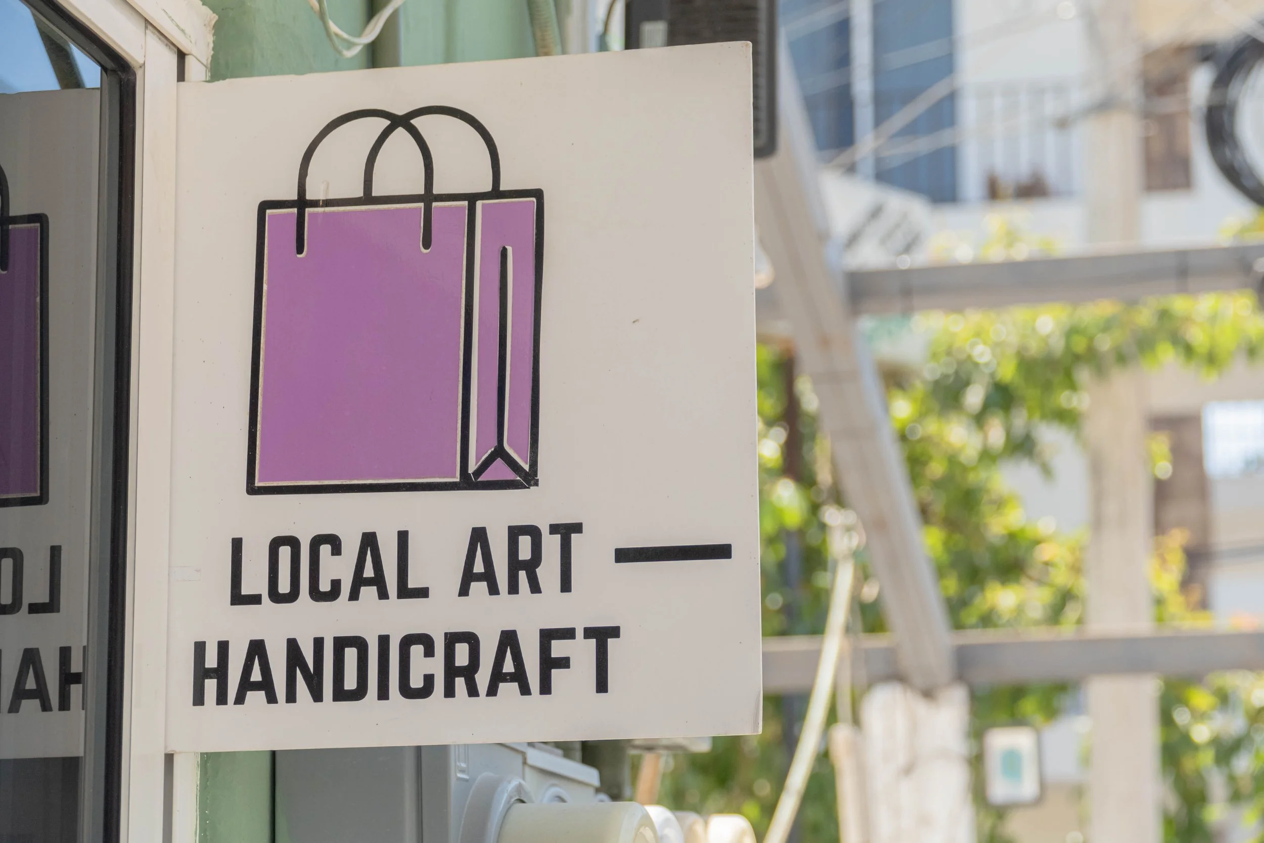 Cartel que dice 'Arte Local y Artesanía' con un icono de una bolsa de compras morada en fondo blanco