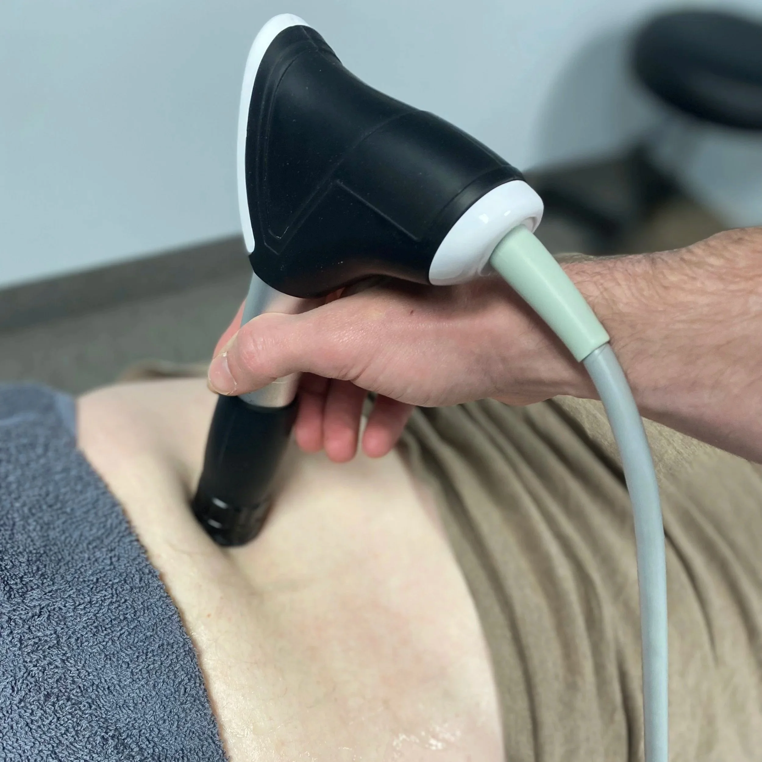 Person getting Shockwave Therapy done on their lower back in the chiropractic office