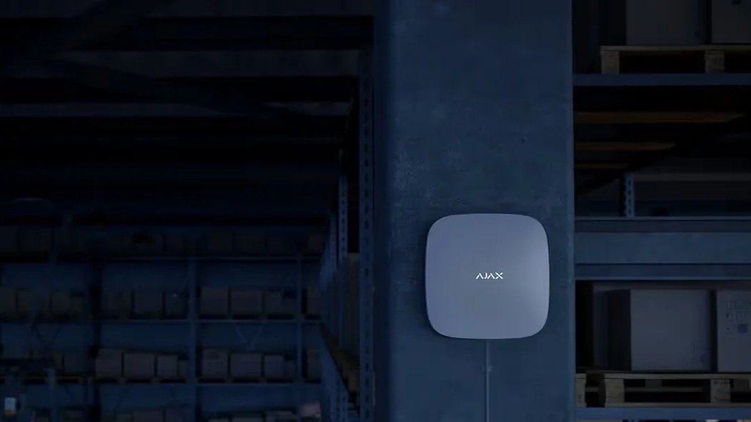 A gray device labeled 'AUX' mounted on a concrete pillar in a warehouse or storage facility.