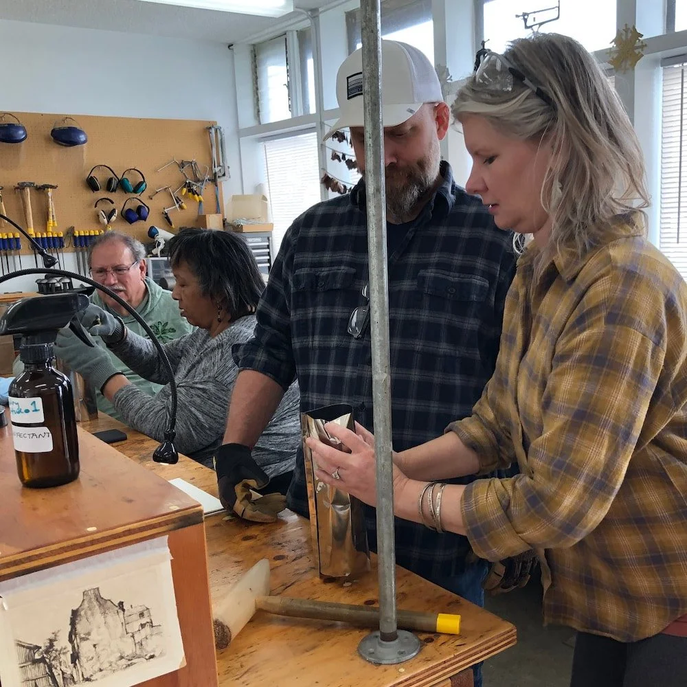Scrubbed and stacked billets have been put in their torque plates, and nestled into a stainless foil bag with charcoal. Michelle is closing up the bag so oxygen can't get in.