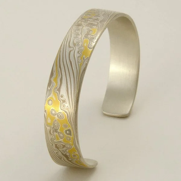 After sweat-soldering on a heavy silver backing, I form the blank into bracelet shape, then do lots more sanding and filing. Last step is etching in nitric acid.