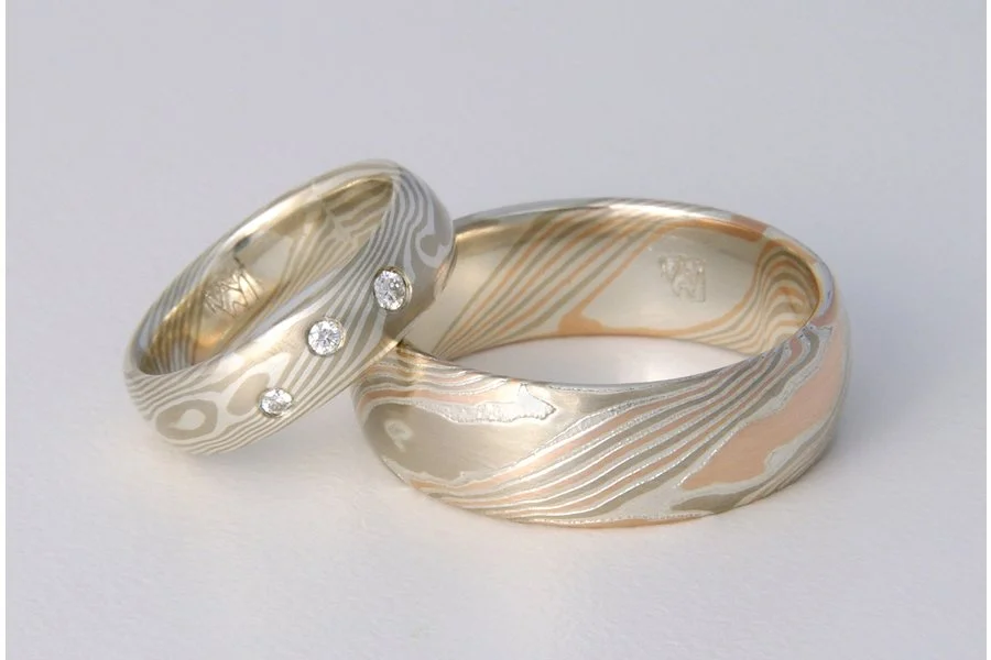 Couples don't have to choose the same mokume material! This pair uses sterling silver with white gold (WS) and three small diamonds for her ring, and 14k palladium white gold, 14k rose gold and sterling silver (WRS) for his.