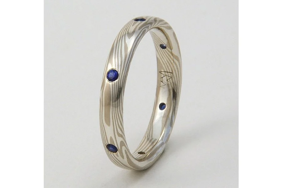 I love the way these tiny sapphires look, flush-set in 14k palladium white gold and sterling silver mokume gane (WS). This was made as a narrow wedding band, to be worn with an engagement ring. This ring is 3.5mm wide, about as narrow as I like to go