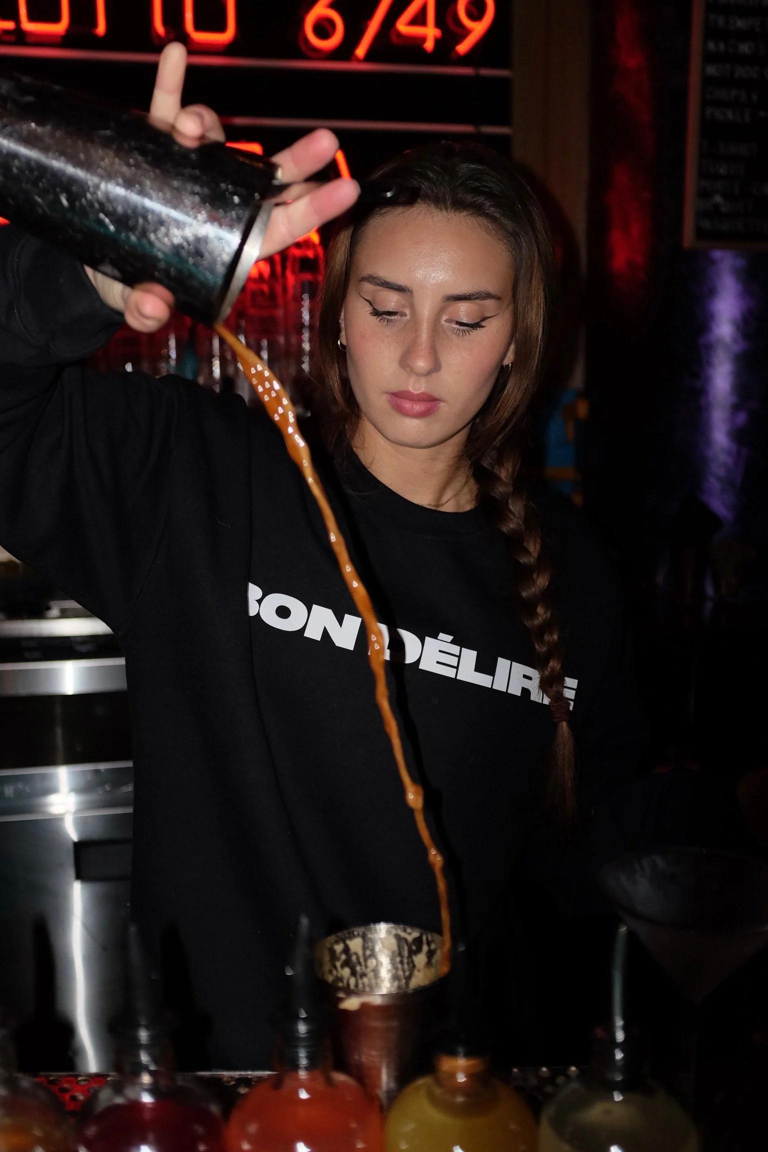 Verre transparent rempli de boisson rosée avec glaçons, garnie d'un quartier de pamplemousse