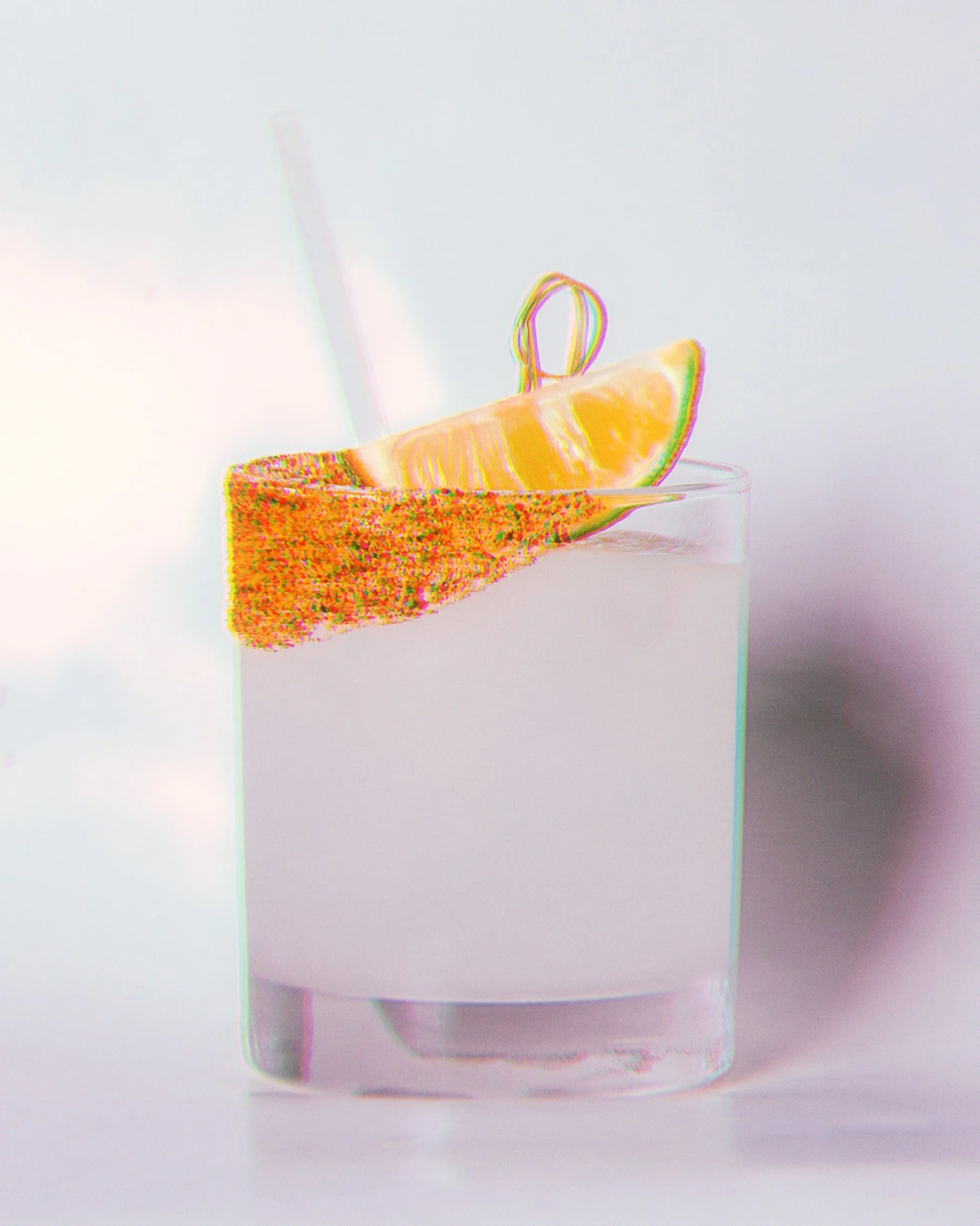 Verre avec une tranche de citron, une sucette en ruban coloré et un morceau de gâteau aux couleurs vives