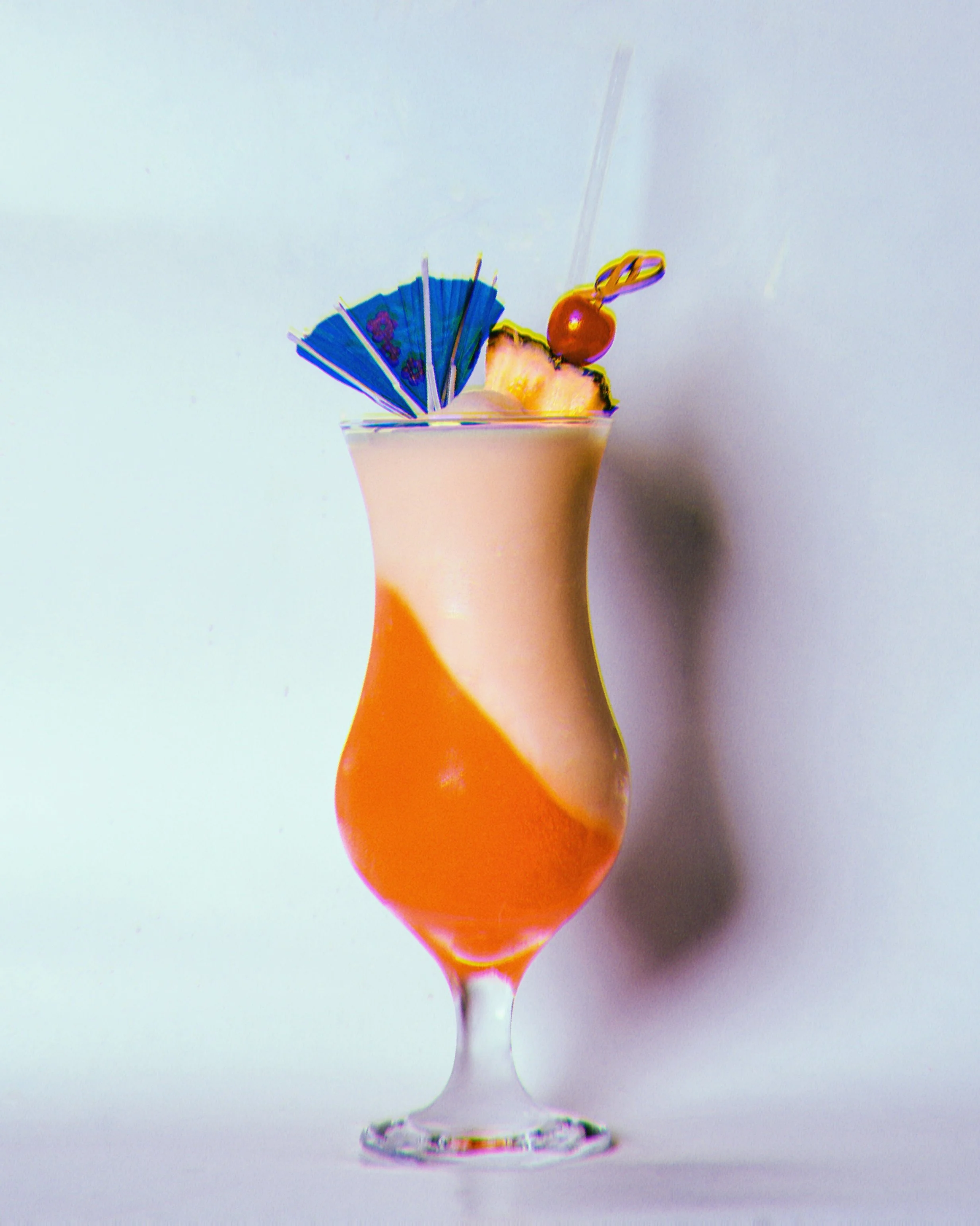 Cocktail coloré avec garnitures de fruit, une petite ombrelle, une cerise et un parasol
