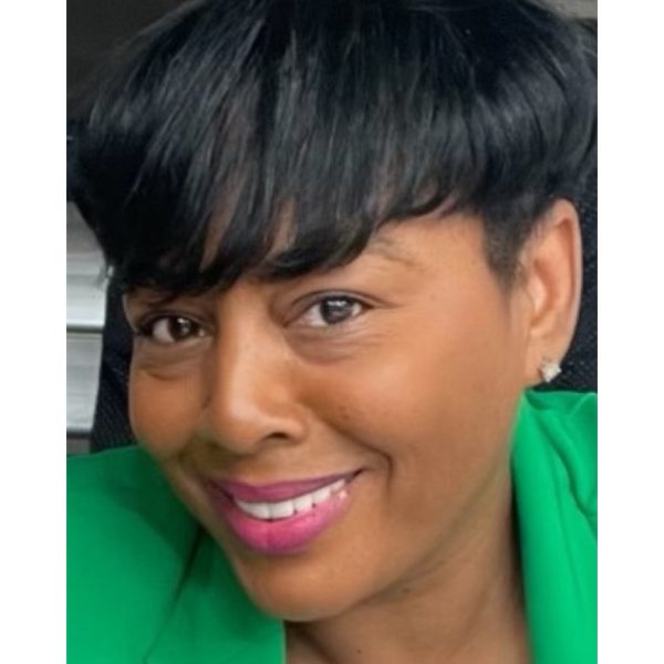 Close-up of a woman with short black hair, wearing a green blazer, pink lipstick, and a diamond earring, smiling.