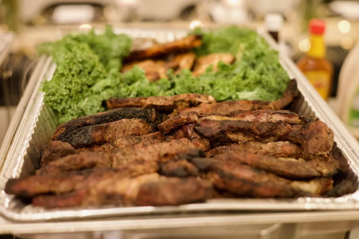 Grilled meat and ribs on a tray with lettuce garnish.