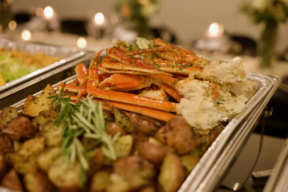 Seafood platter with crab legs, roasted potatoes, and garnishes on a serving tray.