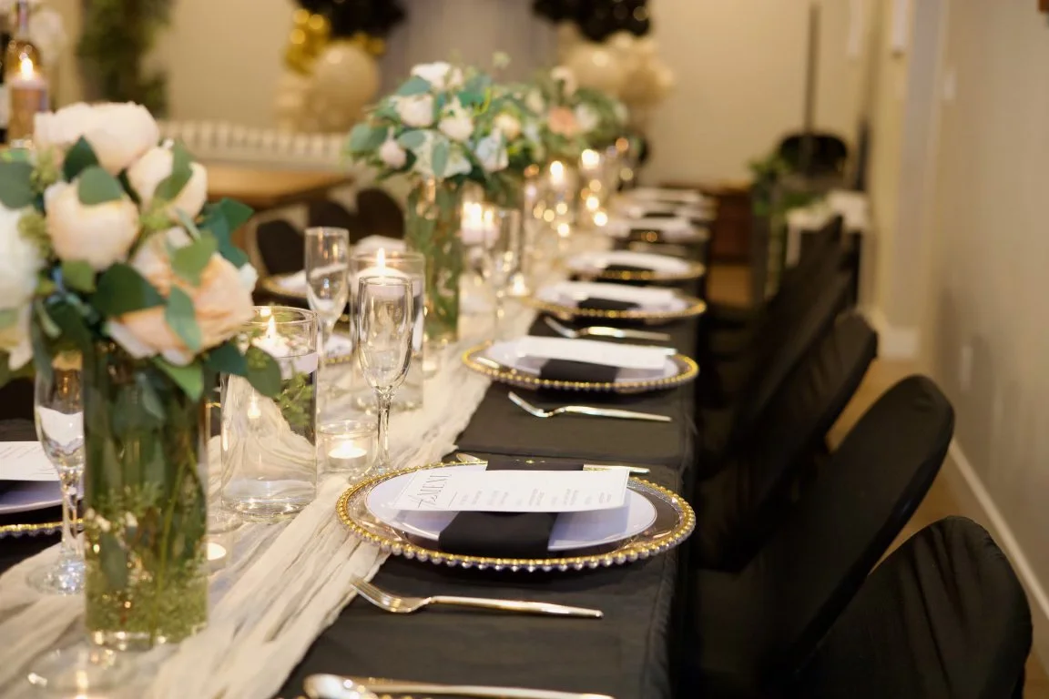 Elegant dinner table setting with floral centerpieces, candles, champagne flutes, and gold-rimmed plates