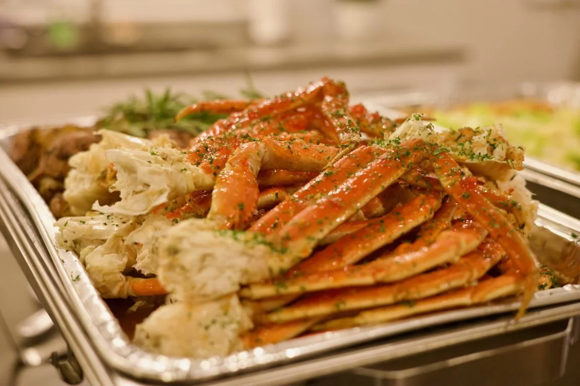 A tray of steamed crab legs with seasoning and parsley garnishing.